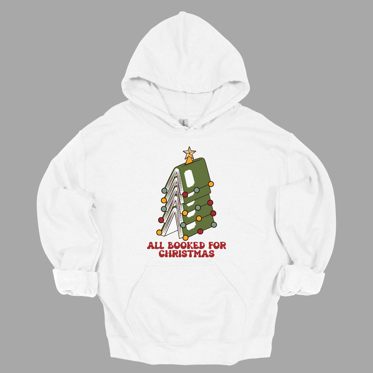 This whimsical t-shirt features the playful phrase "All Booked for Christmas" in a bold, red bubbly font that captures the festive spirit. Above the text, a delightful image showcases a stack of green books, artfully arranged to resemble a decorated Christmas tree. Shop Gorgeousware.com