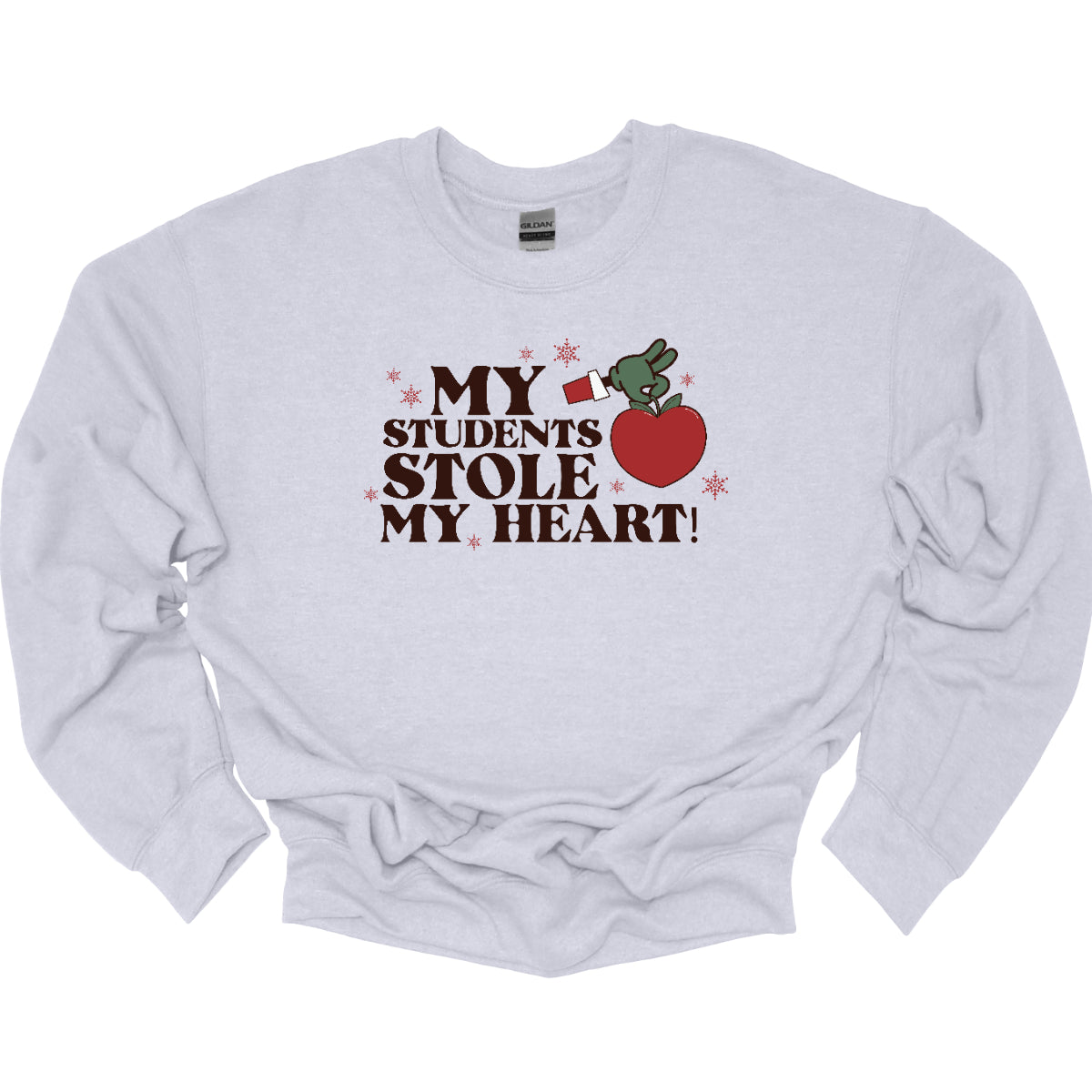 This playful t-shirt features the phrase "My students stole my heart" in fun, whimsical lettering that captures the spirit of teaching. Below the text, a cheeky illustration of the Grinch's green arm emerges, playfully grasping a shiny red apple, symbolizing knowledge and education. Shop at Gorgeousware.com