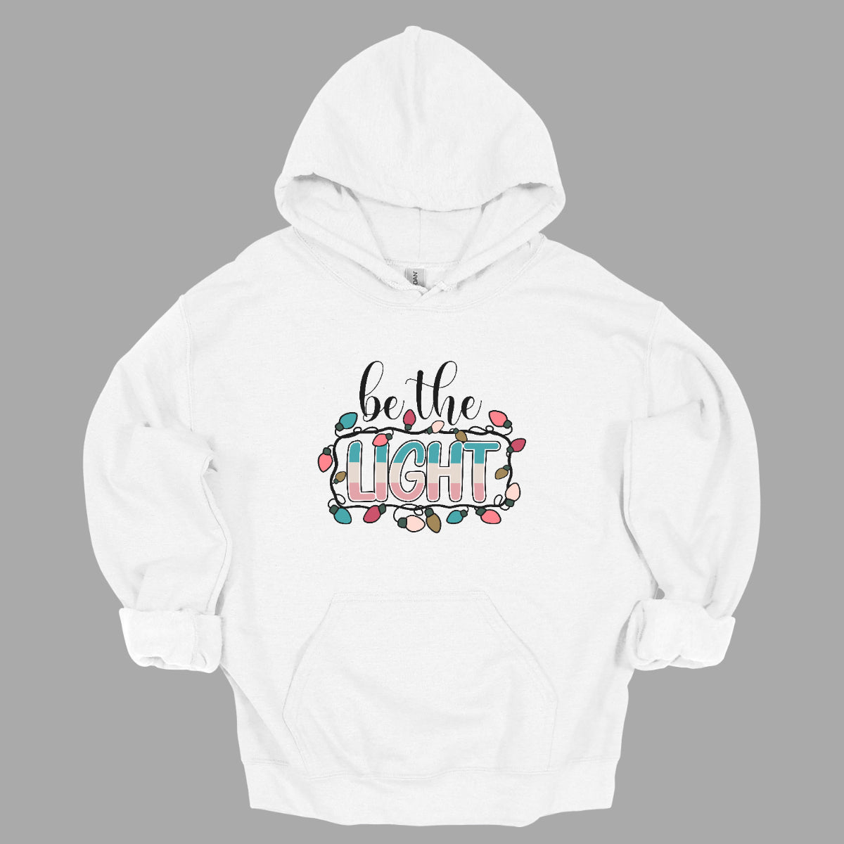 This uplifting t-shirt features the inspiring phrase "Be the Light" in a delightful design. The words "be the" are elegantly written in a flowing black cursive font, adding a touch of sophistication. In contrast, the word "light" bursts forth in a fun, bubbly font, showcasing a vibrant mix of colors that radiate positivity. Surrounding "light" is a charming strand of colorful Christmas lights, twinkling playfully and enhancing the festive spirit of the shirt. Shop Gorgeousware.com