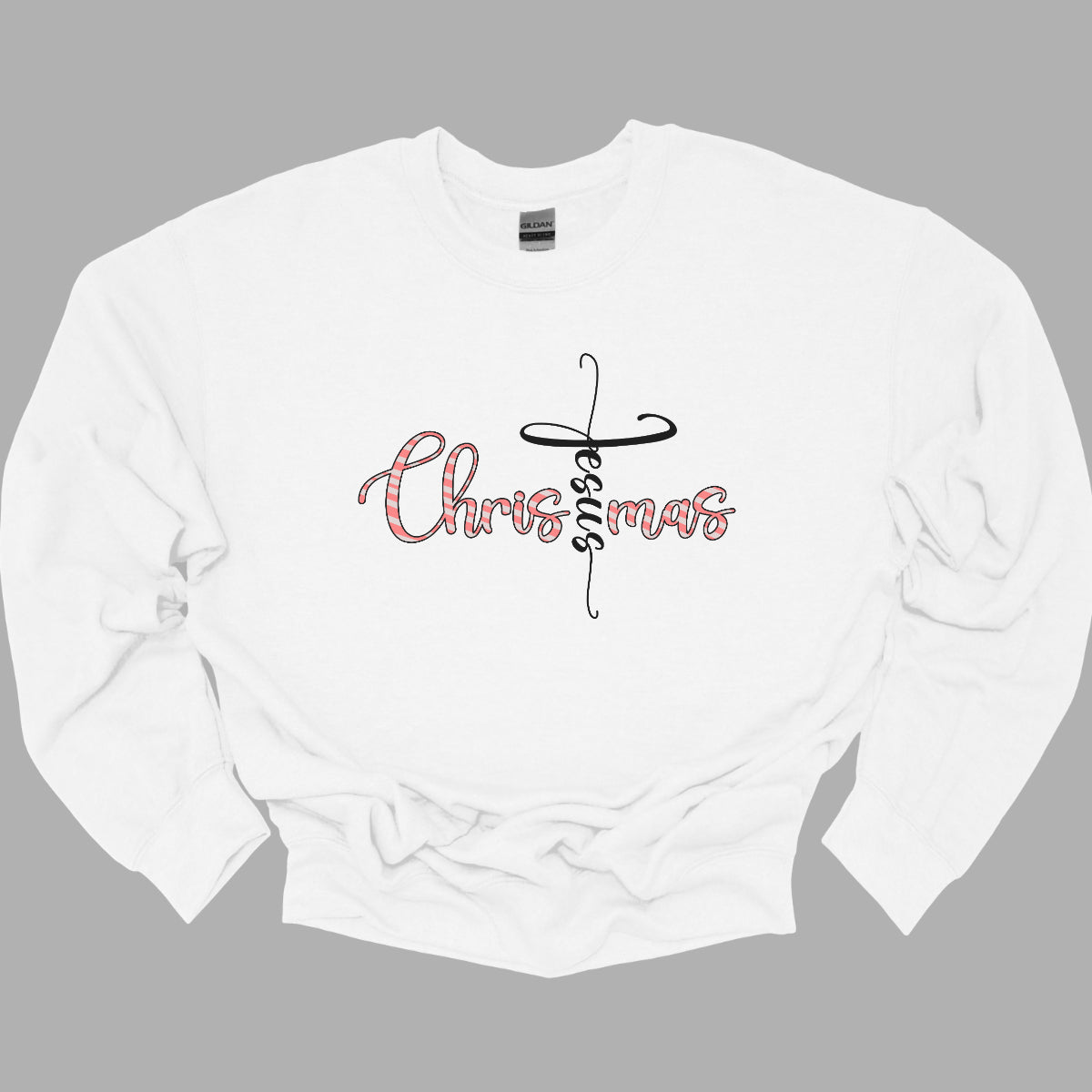 This charming t-shirt features the word "Christmas" in a delightful bubbly cursive font, designed with festive white and red stripes to mimic a candy cane. A unique twist makes the letter "t" stand out as the word "Jesus" rendered in elegant black cursive font. This creative design beautifully blends holiday spirit with a meaningful message, making it a perfect choice for celebrating the season in style and faith! Shop Gorgeousware.com
