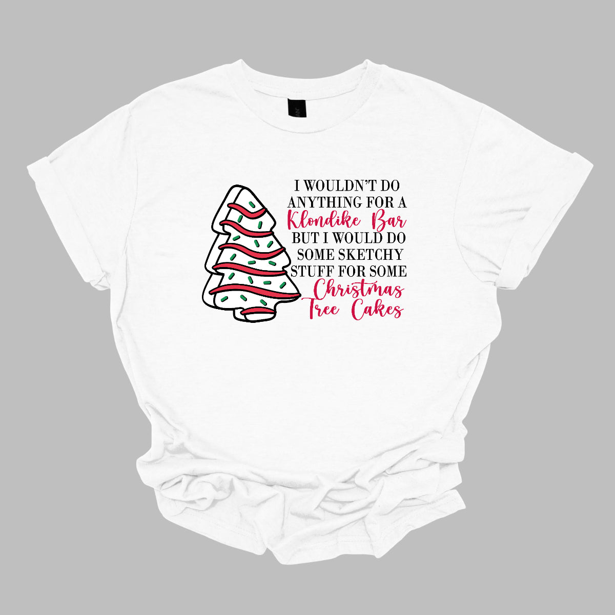 This fun t-shirt features a playful phrase: "I wouldn't do anything for a Klondike Bar but I would do some sketchy stuff for some Christmas Tree Cakes." The main text is presented in a sleek, professional black font, offering a clean contrast to the whimsical red cursive font used for "Klondike Bar" and "Christmas Tree Cakes," drawing attention to those key phrases. Shop Gorgeousware.com