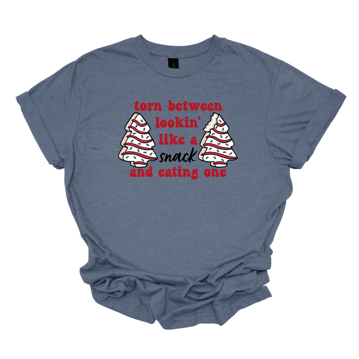 This fun t-shirt features the playful phrase "Torn between lookin' like a snack and eating one" in a vibrant red bubbly font, adding a lively and festive touch. The word "snack" stands out in an elegant black cursive font, creating a nice contrast. Flanking the text are adorable illustrations of Christmas tree cakes on each side, enhancing the holiday spirit and adding a whimsical flair. This shirt is perfect for anyone who loves to celebrate the season with humor and style! Shop Gorgeousware.com