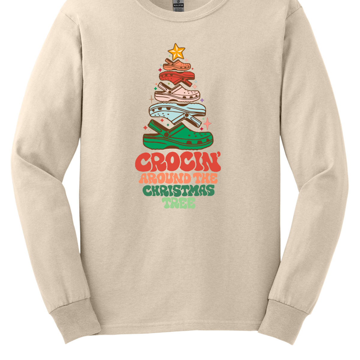 This fun t-shirt features the playful phrase "Crockin' Around the Christmas Tree" in a retro-inspired font that combines vibrant reds and greens for a festive touch. The centerpiece of the design is a whimsical Christmas tree crafted entirely from colorful croc shoes, stacked creatively to form the classic shape. Topping off the tree is a shiny star, adding a delightful finishing touch. Shop at Gorgeousware.com