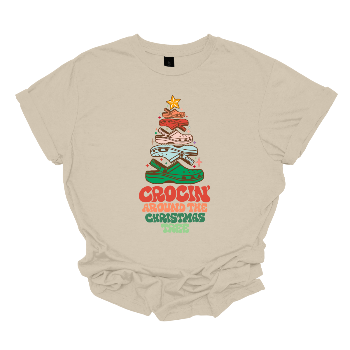 This fun t-shirt features the playful phrase "Crockin' Around the Christmas Tree" in a retro-inspired font that combines vibrant reds and greens for a festive touch. The centerpiece of the design is a whimsical Christmas tree crafted entirely from colorful croc shoes, stacked creatively to form the classic shape. Topping off the tree is a shiny star, adding a delightful finishing touch. Shop at Gorgeousware.com