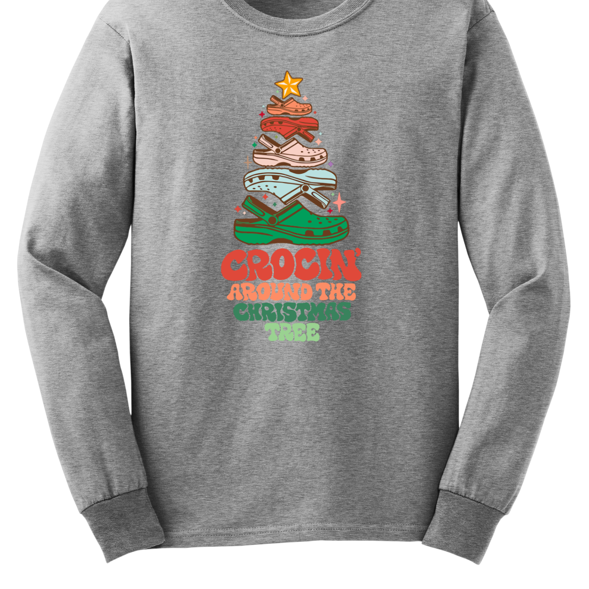 This fun t-shirt features the playful phrase "Crockin' Around the Christmas Tree" in a retro-inspired font that combines vibrant reds and greens for a festive touch. The centerpiece of the design is a whimsical Christmas tree crafted entirely from colorful croc shoes, stacked creatively to form the classic shape. Topping off the tree is a shiny star, adding a delightful finishing touch. Shop at Gorgeousware.com