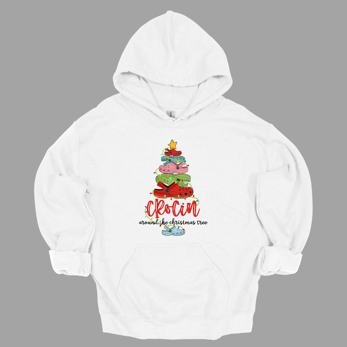 This playful t-shirt features the fun phrase "Crockin' Around the Christmas Tree" with a unique twist. The word "Crockin'" is showcased in a vibrant red cursive font, with playful spaces between the letters, adding a whimsical flair. Below that, the rest of the phrase is written in a smaller, elegant black cursive font, providing a charming contrast. Shop Gorgeousware.com
