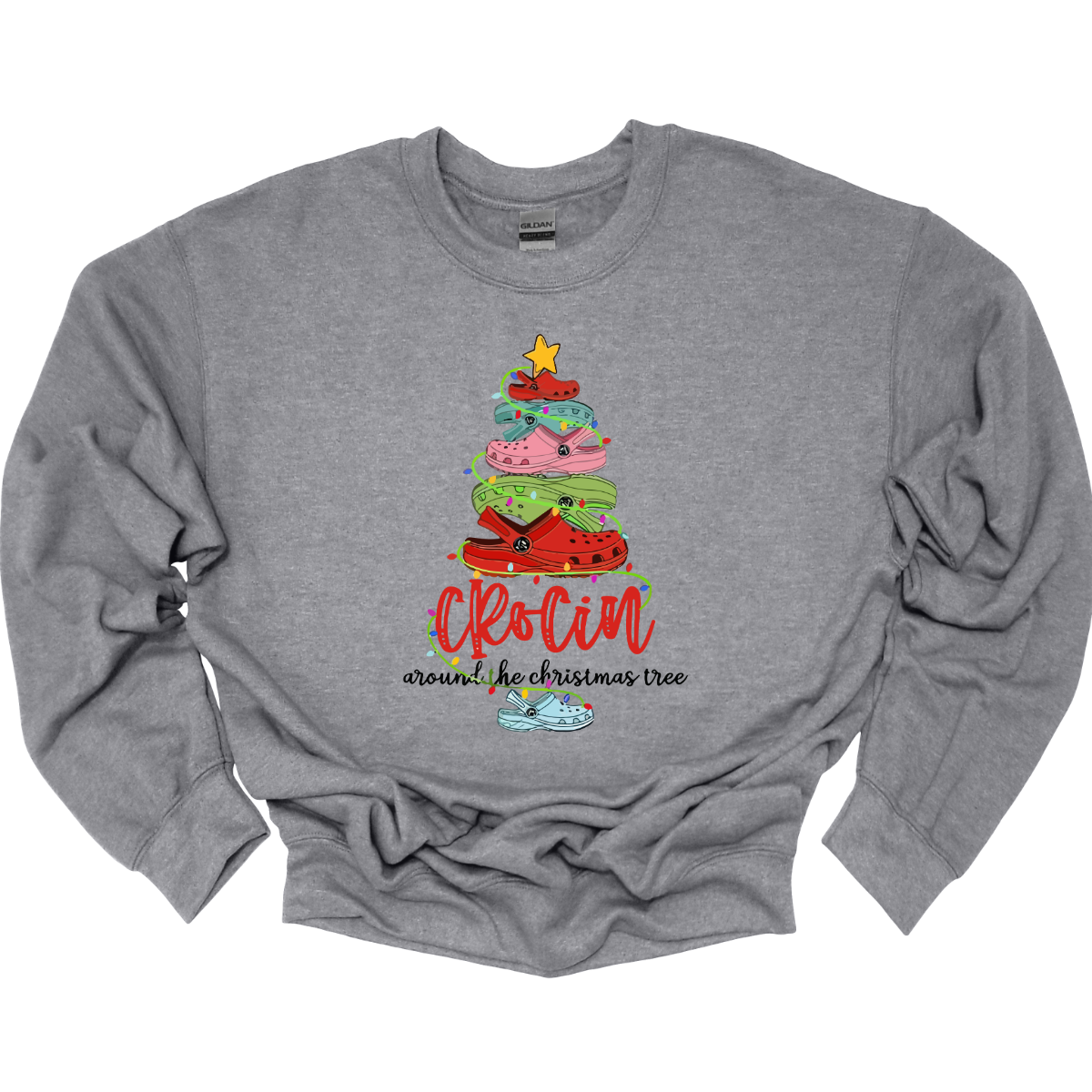 This playful t-shirt features the fun phrase "Crockin' Around the Christmas Tree" with a unique twist. The word "Crockin'" is showcased in a vibrant red cursive font, with playful spaces between the letters, adding a whimsical flair. Below that, the rest of the phrase is written in a smaller, elegant black cursive font, providing a charming contrast. Shop Gorgeousware.com