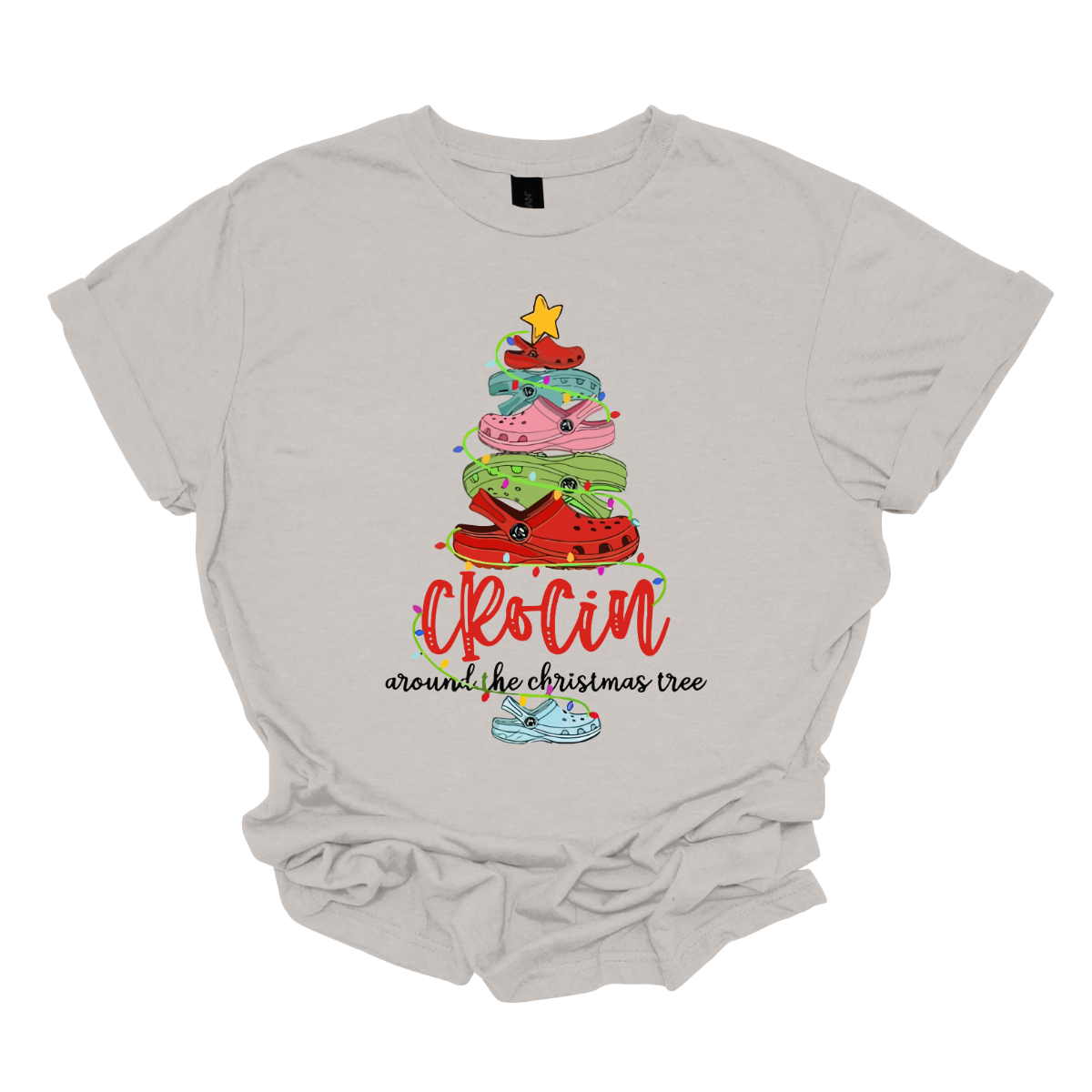 This playful t-shirt features the fun phrase "Crockin' Around the Christmas Tree" with a unique twist. The word "Crockin'" is showcased in a vibrant red cursive font, with playful spaces between the letters, adding a whimsical flair. Below that, the rest of the phrase is written in a smaller, elegant black cursive font, providing a charming contrast. Shop Gorgeousware.com