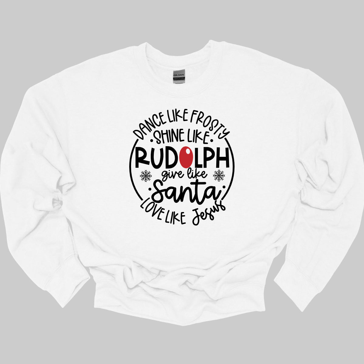 This heartwarming t-shirt features the uplifting phrase "Dance like Frosty, shine like Rudolph, give like Santa, love like Jesus" arranged in an array of stylish black fonts that create a dynamic and eye-catching design. The “O” in "Rudolph" is playfully highlighted in red, resembling his famous nose, adding a festive touch to the overall look. Shop Gorgeousware.com