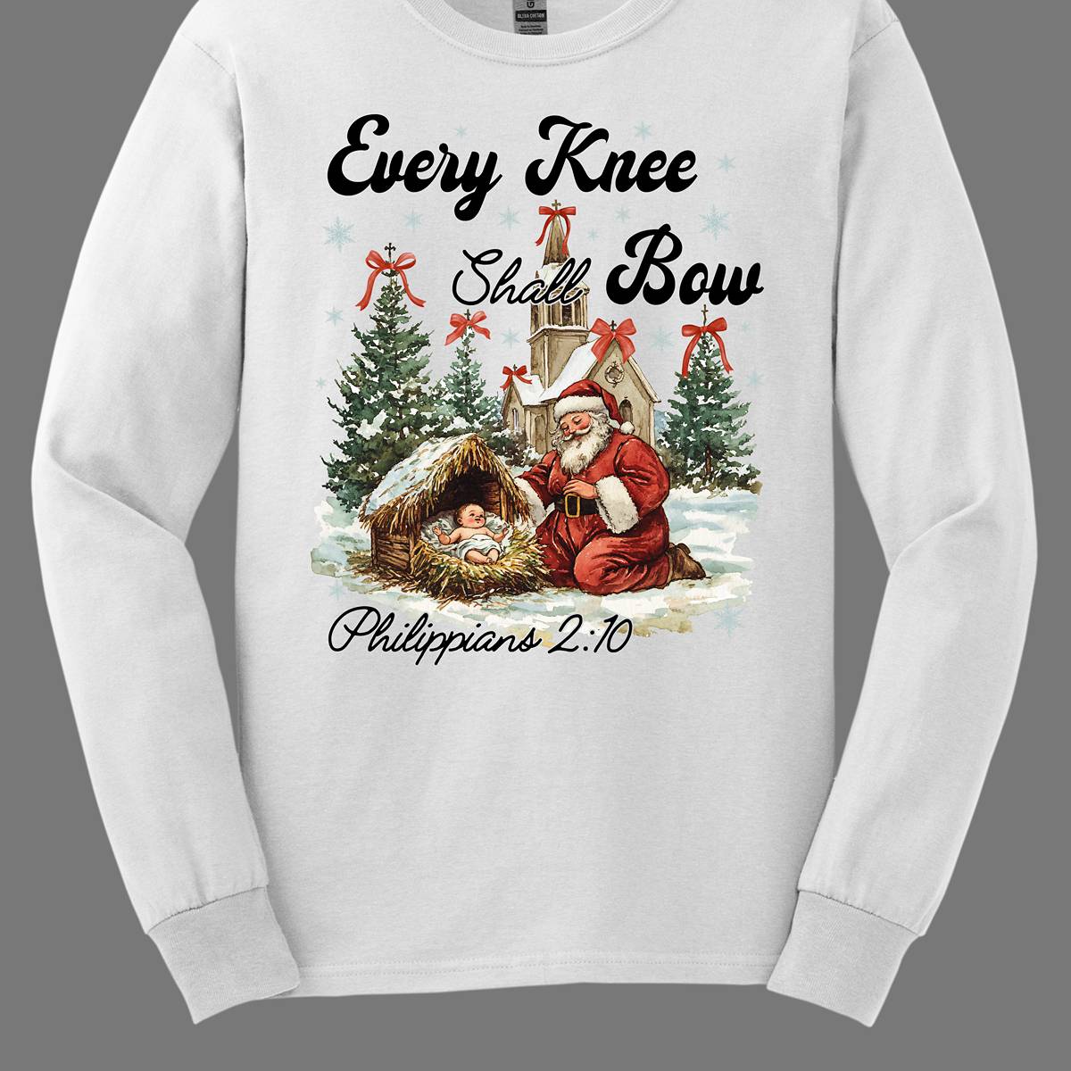 This festive and powerful apparel design features the phrase "Every Knee Shall Bow" in bold, elegant lettering, symbolizing the reverence and humility of the Christmas story. The artwork showcases Santa Claus, traditionally known for his joyful spirit, bowing down in awe before a humble manger that cradles baby Jesus. In the background, an old chapel stands as a symbol of faith, with evergreen trees adorned with festive bows, adding a touch of seasonal beauty and serenity. Shop at Gorgeousware.com