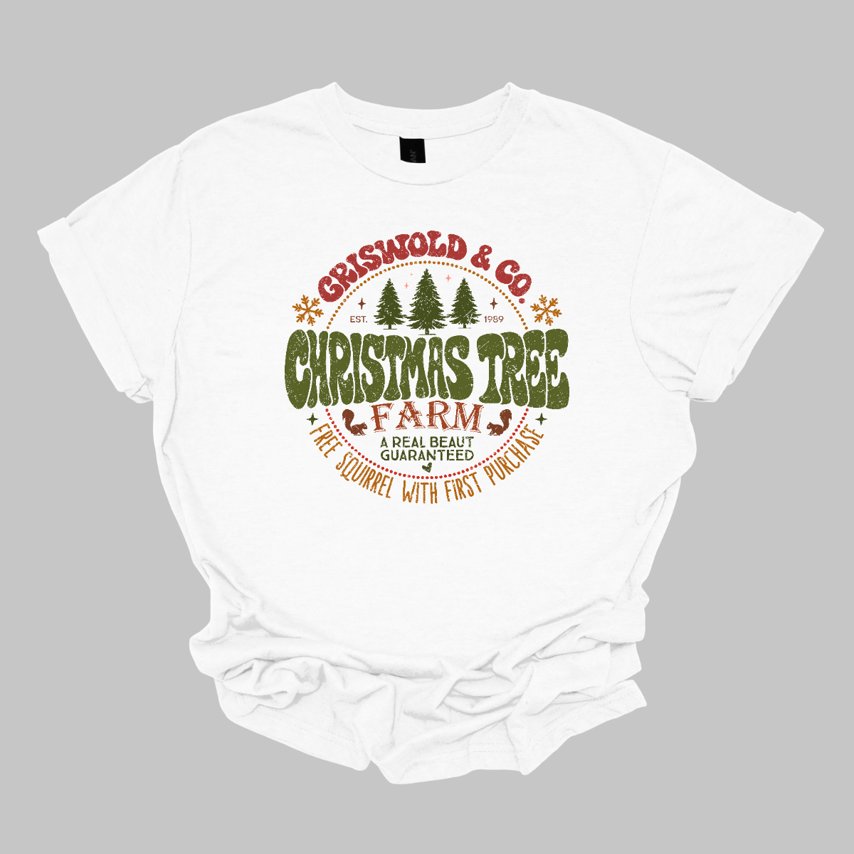 This festive t-shirt captures the spirit of holiday fun with a design inspired by classic Christmas cheer. The shirt features the words “Christmas Tree Farm” prominently displayed, with “Christmas Tree” in vibrant green bubble letters that pop with playful energy.Encircling this central text is “Griswold & CO.,” giving it a nostalgic nod to the iconic family from holiday movie lore. Surrounding the main text are memorable quotes from the movie. Shop Gorgeousware.com