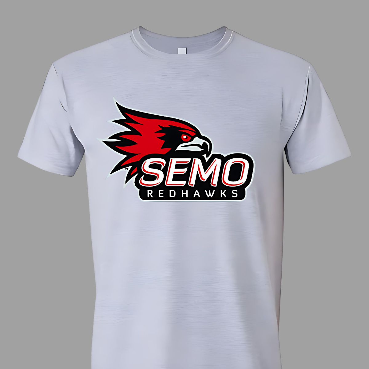 This vibrant t-shirt features the iconic SEMO Redhawk logo prominently displayed at the top, showcasing the fierce spirit of the team. Below the hawk, bold bubble letters spell out "SEMO," creating a playful and eye-catching design. Just underneath, in smaller, stylish print, the word "Redhawks" completes the look, making it a perfect blend of fun and team pride.  Shop at Gorgeousware.com