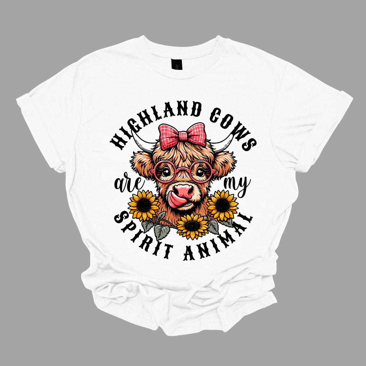 This shirt showcases a delightful Highland cow, complete with a cute bow on its head and stylish glasses, radiating charm and personality. Beneath the cow, a lovely arrangement of yellow daisies creates a soft, floral touch, adding a pop of color and whimsy to the design. The phrase "Highland Cows are my spirit animal" is playfully displayed, capturing the cow's spirit and the wearer's connection to these unique creatures. Shop Gorgeouseware.com
