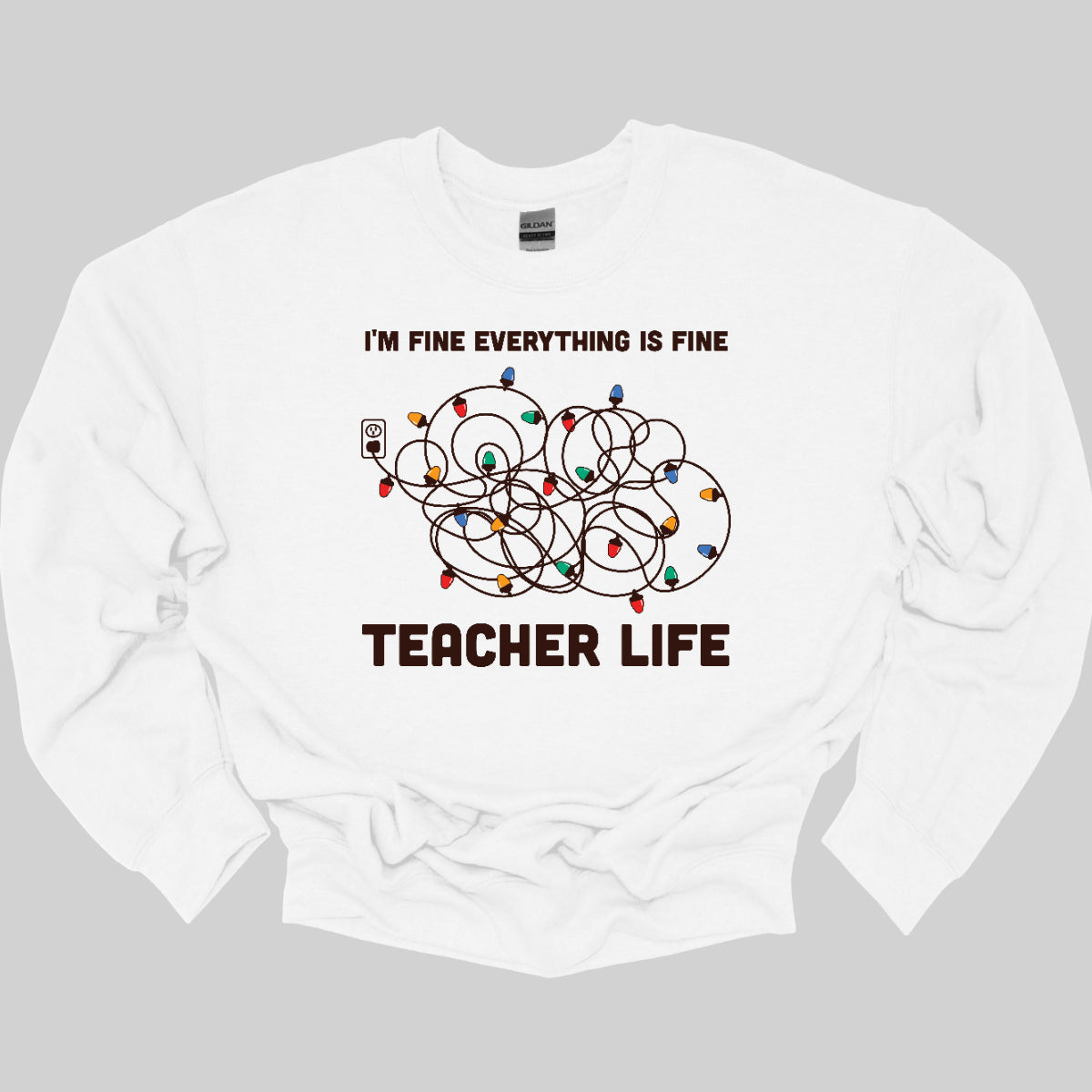 This humorous t-shirt features the phrase "I'm fine, everything is fine" in bold, playful lettering, perfectly capturing that relatable holiday vibe. Below the text, there's a whimsical illustration of a tangled wad of Christmas lights plugged into an outlet, humorously representing the chaos that can come with the season. Underneath the lights, the words "Teacher Life" are displayed, adding a clever nod to the unique challenges teachers face, especially during the festive rush. Shop at Gorgeousware.com