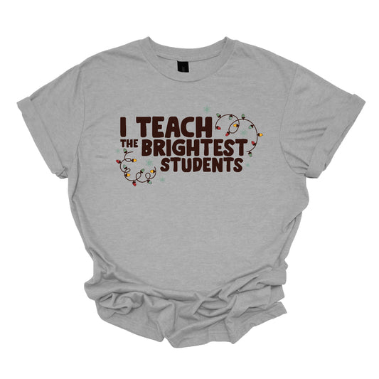 Celebrate your passion for teaching with our "I Teach the Brightest Students" t-shirt! This fun and festive design features cheerful Christmas lights framing the text, adding a touch of holiday spirit to your classroom vibe. Made from soft, comfortable fabric, it’s perfect for wearing during the festive season or any day you want to show off your pride in your students. Brighten up your wardrobe and spread some joy—because every great teacher deserves to shine! Shop at Gorgeousware.com