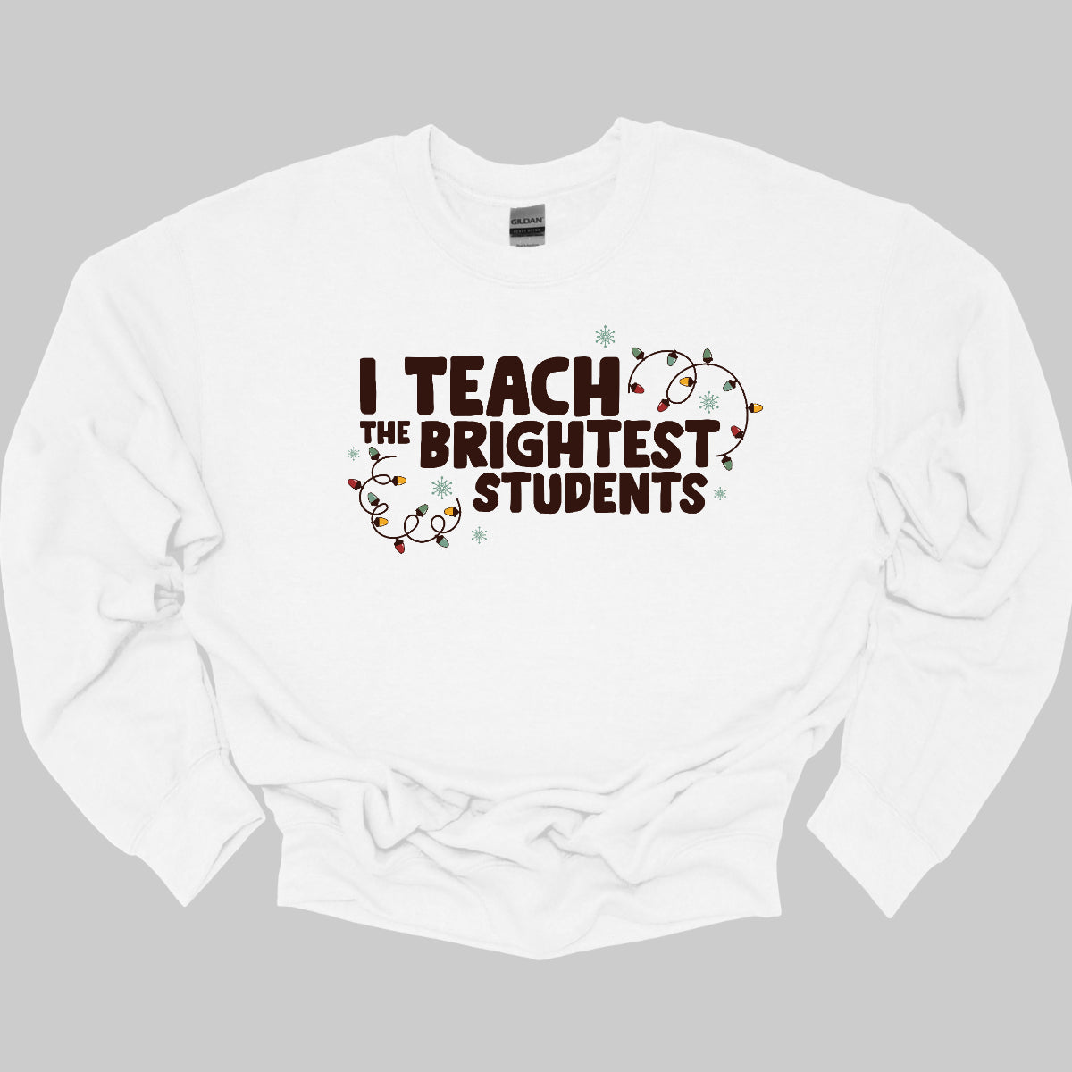 Celebrate your passion for teaching with our "I Teach the Brightest Students" t-shirt! This fun and festive design features cheerful Christmas lights framing the text, adding a touch of holiday spirit to your classroom vibe. Made from soft, comfortable fabric, it’s perfect for wearing during the festive season or any day you want to show off your pride in your students. Brighten up your wardrobe and spread some joy—because every great teacher deserves to