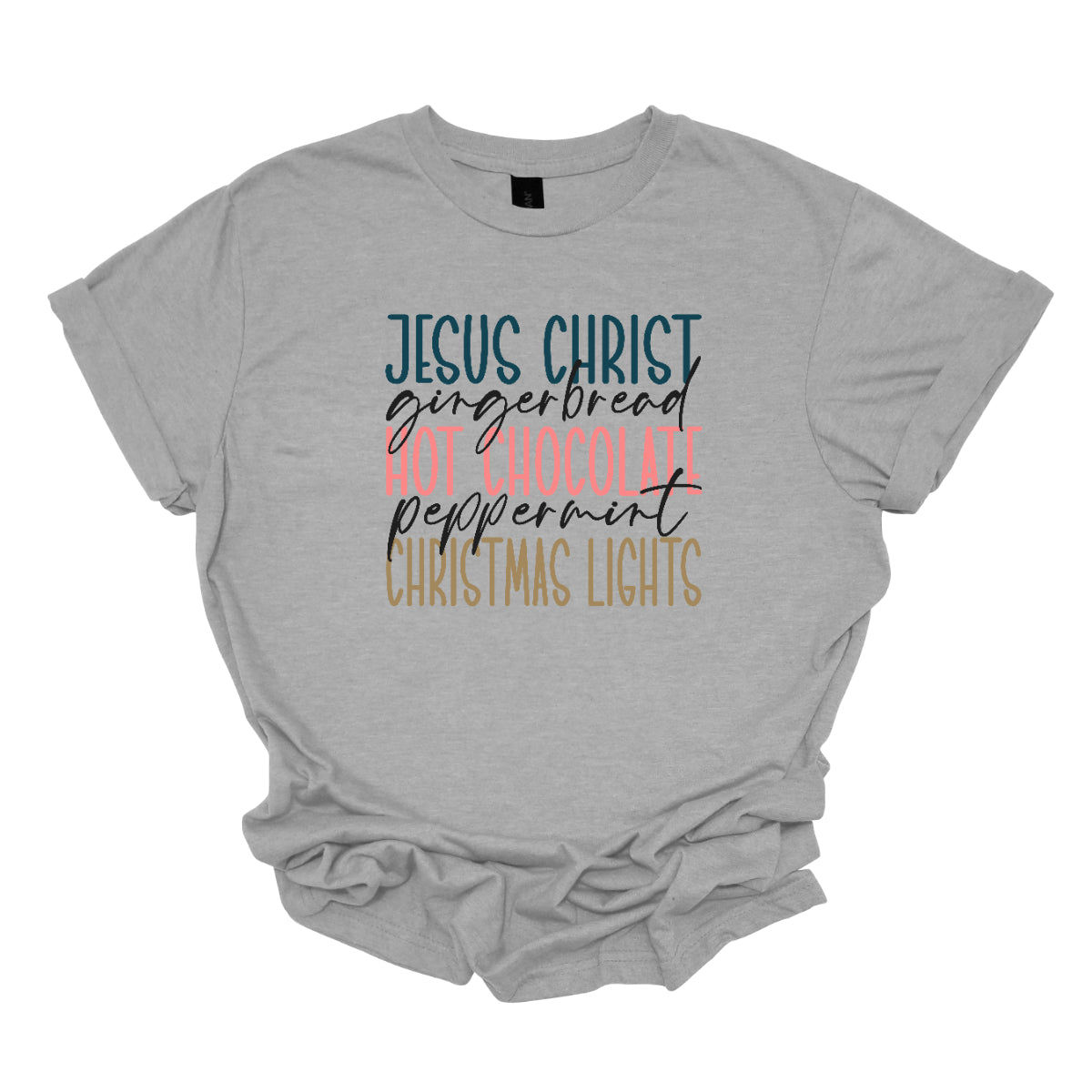 This festive t-shirt showcases a vibrant design with the phrase "JESUS CHRIST," "gingerbread," "HOT CHOCOLATE," "peppermint," and "CHRISTMAS LIGHTS" arranged vertically down the shirt. The words "JESUS CHRIST," "HOT CHOCOLATE," and "CHRISTMAS LIGHTS" are all in bold capital letters, each presented in a different bright color, creating a cheerful and eye-catching effect. Shop Gorgeousware.com