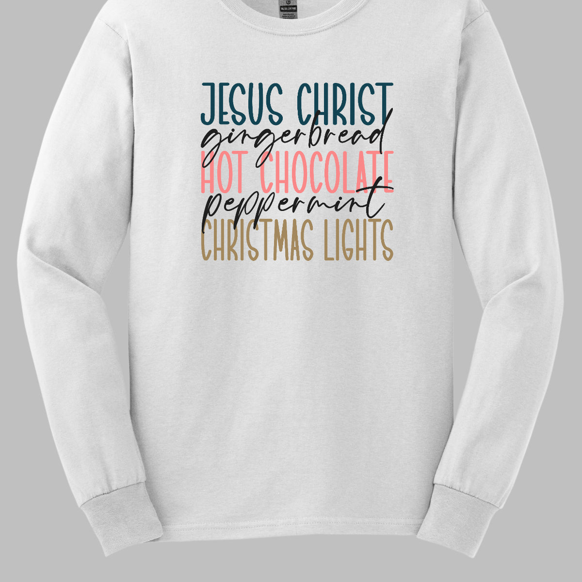 This festive t-shirt showcases a vibrant design with the phrase "JESUS CHRIST," "gingerbread," "HOT CHOCOLATE," "peppermint," and "CHRISTMAS LIGHTS" arranged vertically down the shirt. The words "JESUS CHRIST," "HOT CHOCOLATE," and "CHRISTMAS LIGHTS" are all in bold capital letters, each presented in a different bright color, creating a cheerful and eye-catching effect. Shop Gorgeousware.com