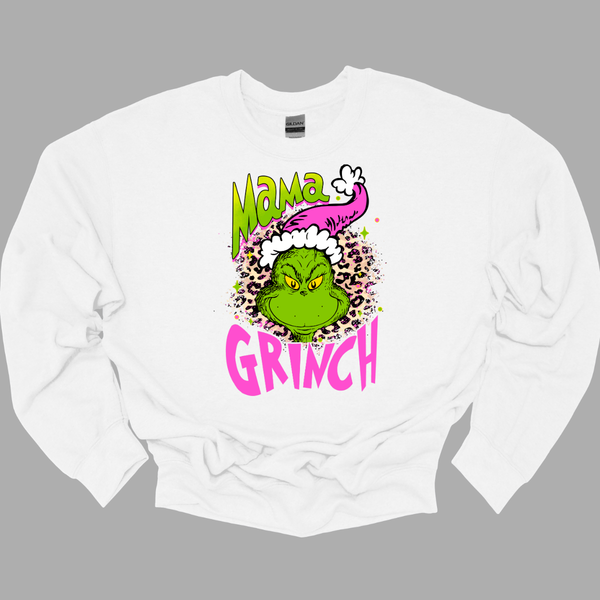 At the center of the design is the phrase "Mama Grinch," rendered in a whimsical, Grinch-style font. The word "Mama" pops in a vibrant green color with a delicate pink shadow that adds a touch of charm. The word "Grinch" contrasts in a bold, eye-catching pink that stands out against the green. Between the two words, there's a delightful illustration of the Grinch himself. He's sporting a cute pink and white Santa hat, which adds a fun and seasonal flair. Shop Gorgeousware.com
