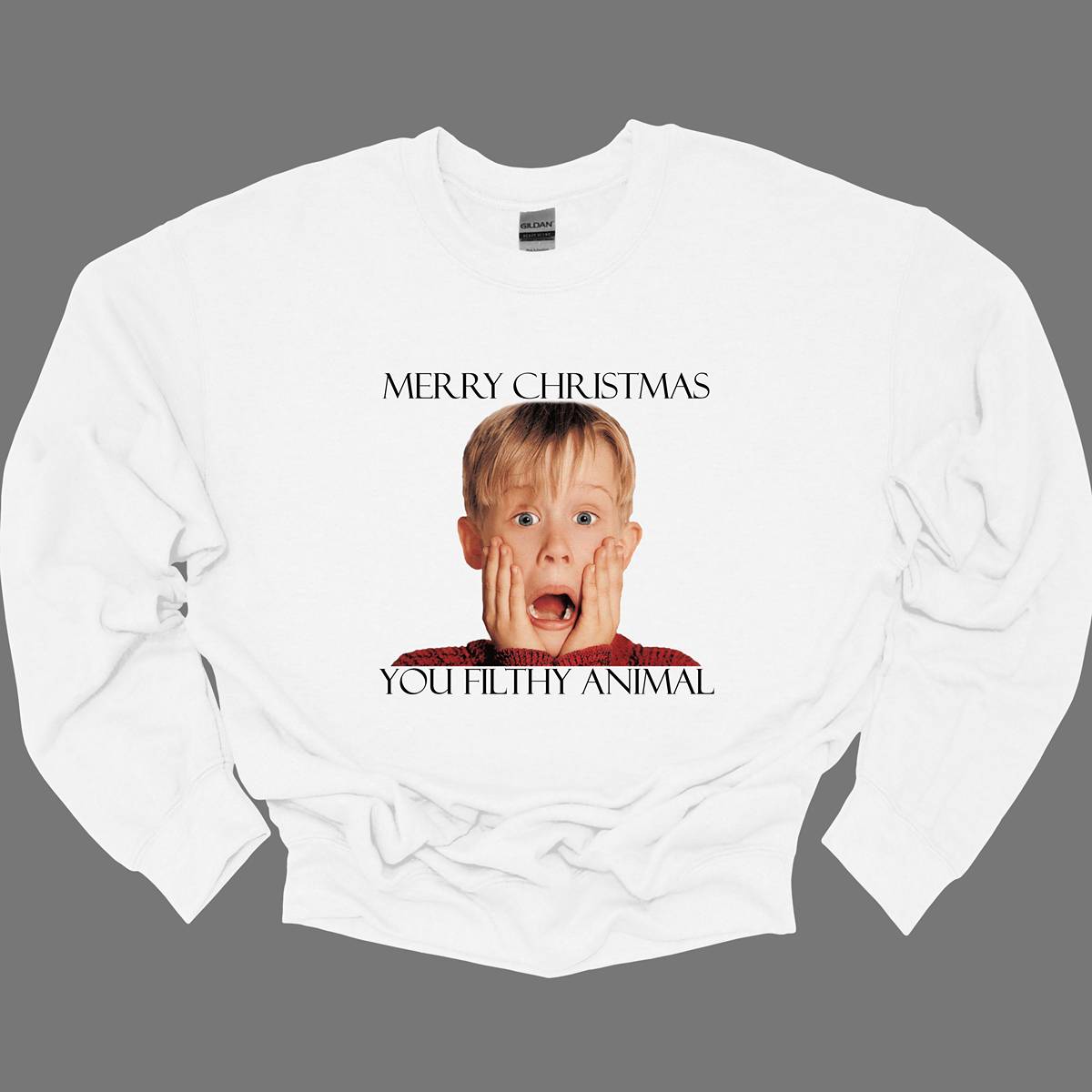 This fun and festive apparel features the iconic phrase "Merry Christmas You Filthy Animal" in bold, playful lettering, a memorable line from the Home Alone movie. The design also showcases the infamous face of Kevin McCallister, played by Macaulay Culkin, with his hands on his cheeks in a dramatic, surprised expression. Perfect for any Home Alone fan, this shirt or sweatshirt is ideal for spreading some holiday cheer and nostalgia. Shop at Gorgeousware.com
