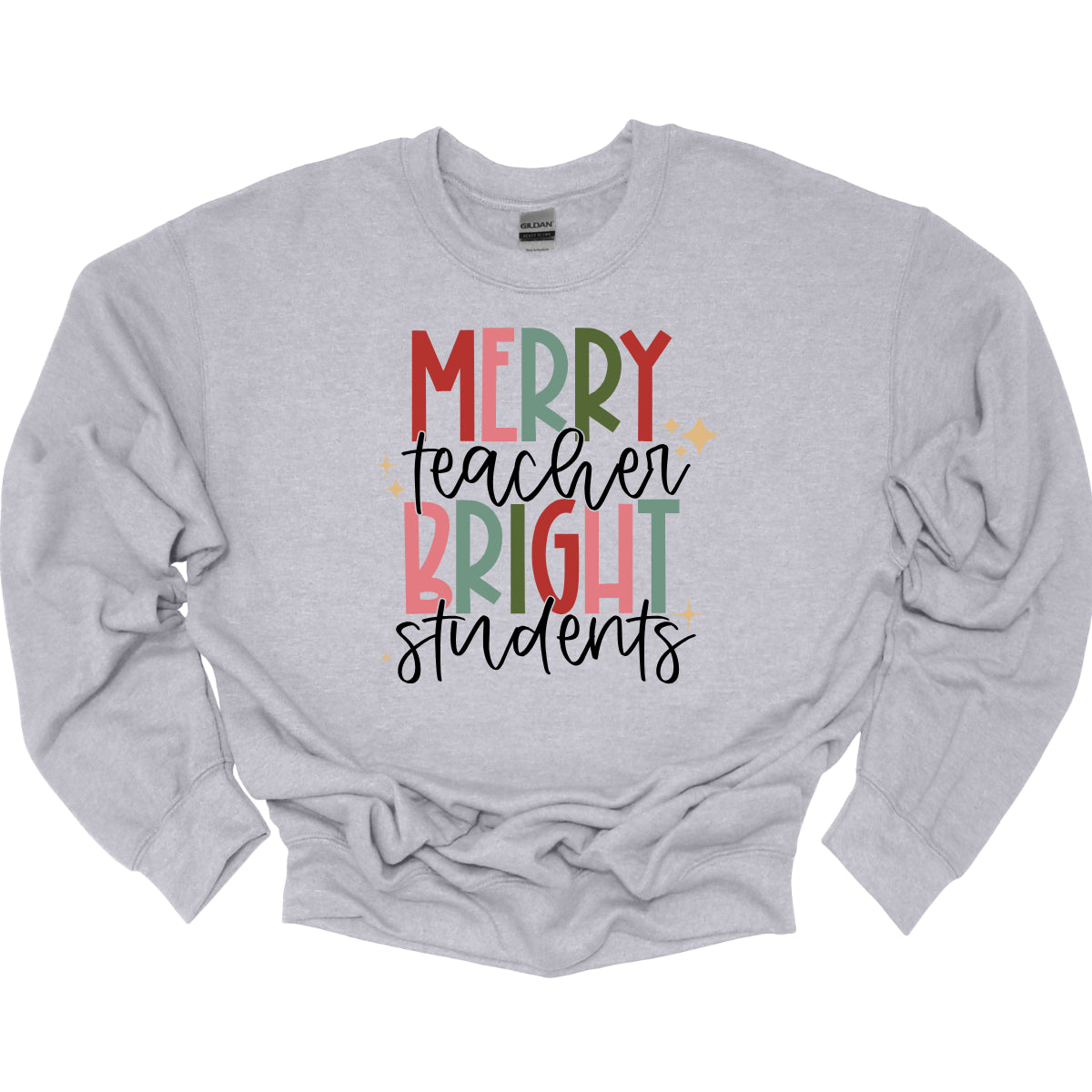 This festive t-shirt showcases the cheerful phrase "Merry Teacher Bright Students" in a delightful design. The words "MERRY" and "BRIGHT" are prominently featured in a blocky yet playful font, with each letter bursting in a vibrant mix of shades of green and red, evoking the spirit of the holiday season. Shop Gorgeousware.com
