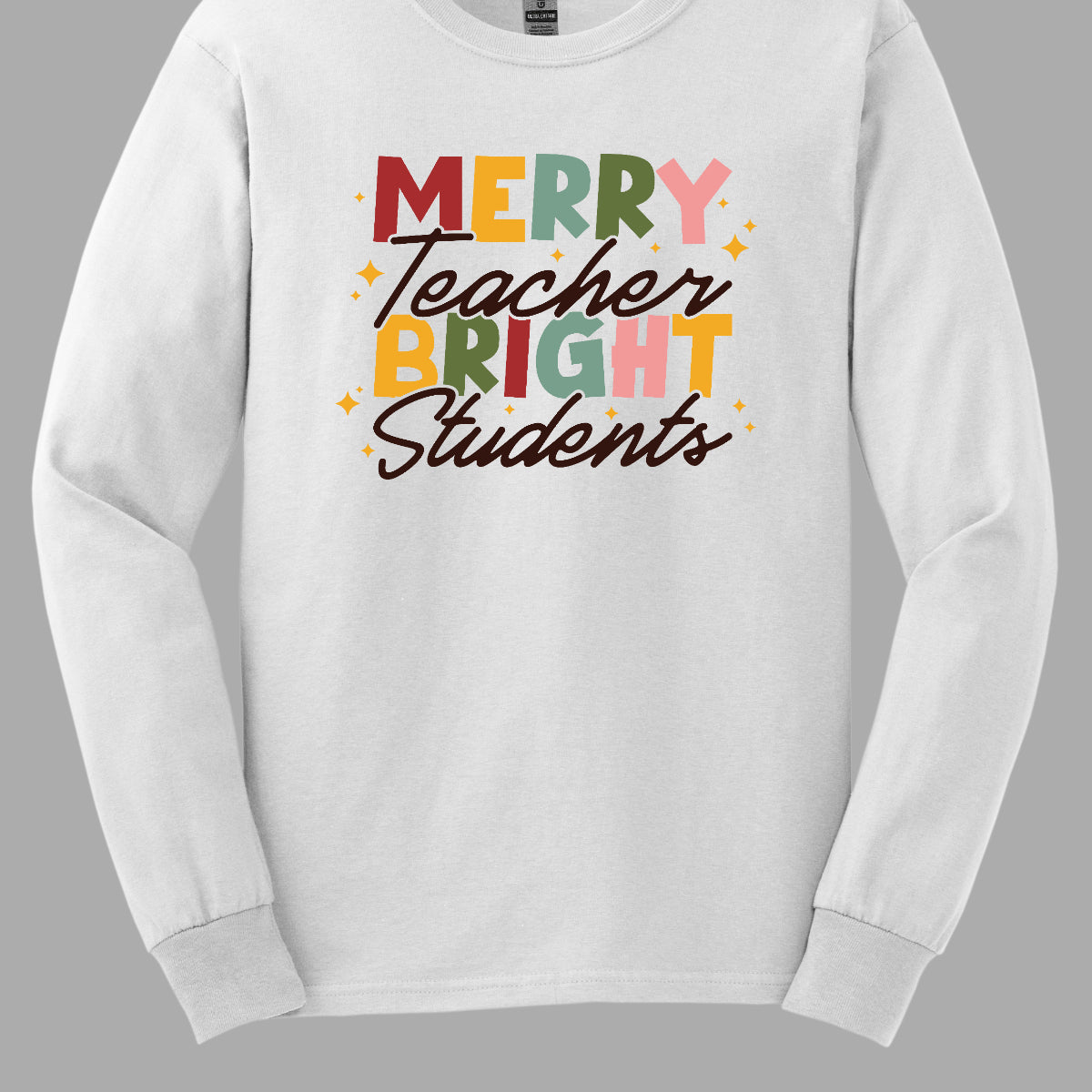 This festive t-shirt showcases the cheerful phrase "Merry Teacher Bright Students" in a delightful design. The words "MERRY" and "BRIGHT" are prominently featured in a blocky yet playful font, with each letter bursting in a vibrant mix of shades of green and red, evoking the spirit of the holiday season. Shop Gorgeousware.com