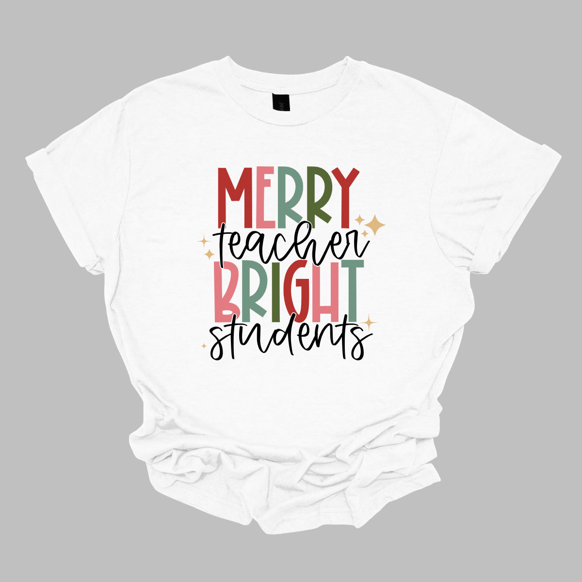 This festive t-shirt showcases the cheerful phrase "Merry Teacher Bright Students" in a delightful design. The words "MERRY" and "BRIGHT" are prominently featured in a blocky yet playful font, with each letter bursting in a vibrant mix of shades of green and red, evoking the spirit of the holiday season. Shop Gorgeousware.com