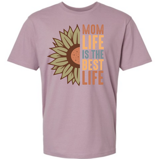 This shirt features the uplifting phrase "Mom Life is the Best Life" in a stylish and modern design. The text is elegantly displayed along one side of the shirt, paired with the image of a large, half-flower graphic. The flower adds a natural, whimsical touch to the design, symbolizing growth and beauty.  Shop Gorgeouseware.com