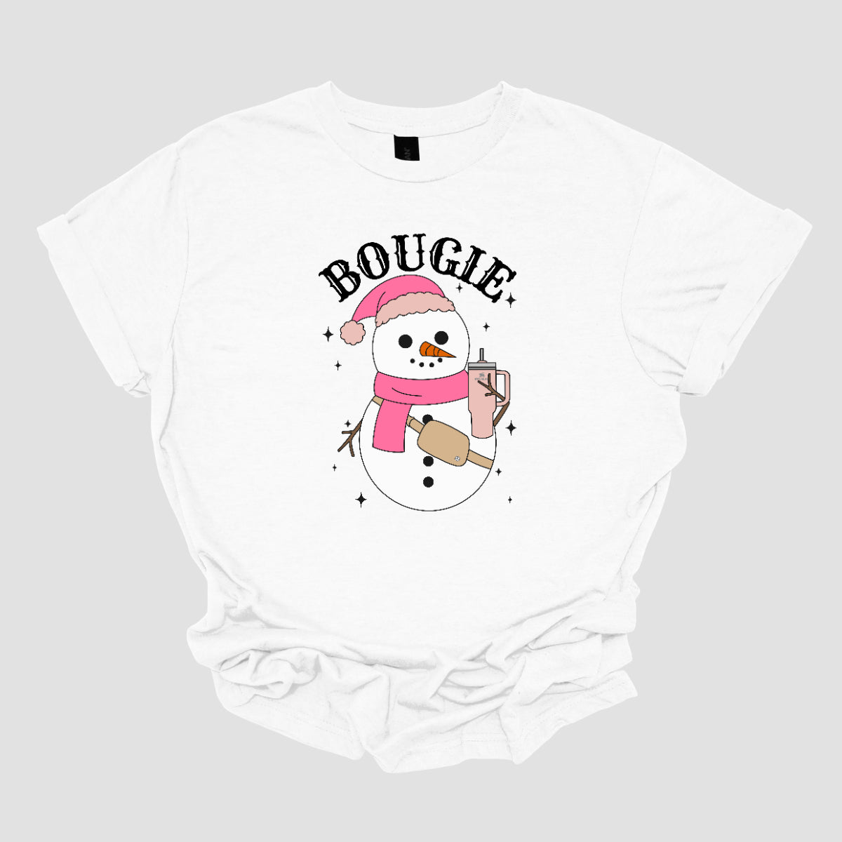 This chic t-shirt features the word "BOUGIE" in elegant, fancy lettering, capturing a stylish vibe. Beneath the text is a charming illustration of a snowman, decked out in a cute pink hat and scarf, exuding festive flair. The snowman is holding a pale pink Stanley cup, adding a trendy touch, while a beige Lululemon belt bag rests around its waist, complete with sparkles that catch the eye and enhance the glamorous theme. Shop Gorgeousware.com