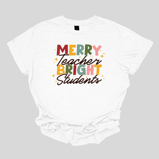 This festive t-shirt showcases the cheerful phrase "Merry Teacher Bright Students" in a delightful design. The words "MERRY" and "BRIGHT" are prominently featured in a blocky yet playful font, with each letter bursting in a vibrant mix of shades of green and red, evoking the spirit of the holiday season. Shop Gorgeousware.com