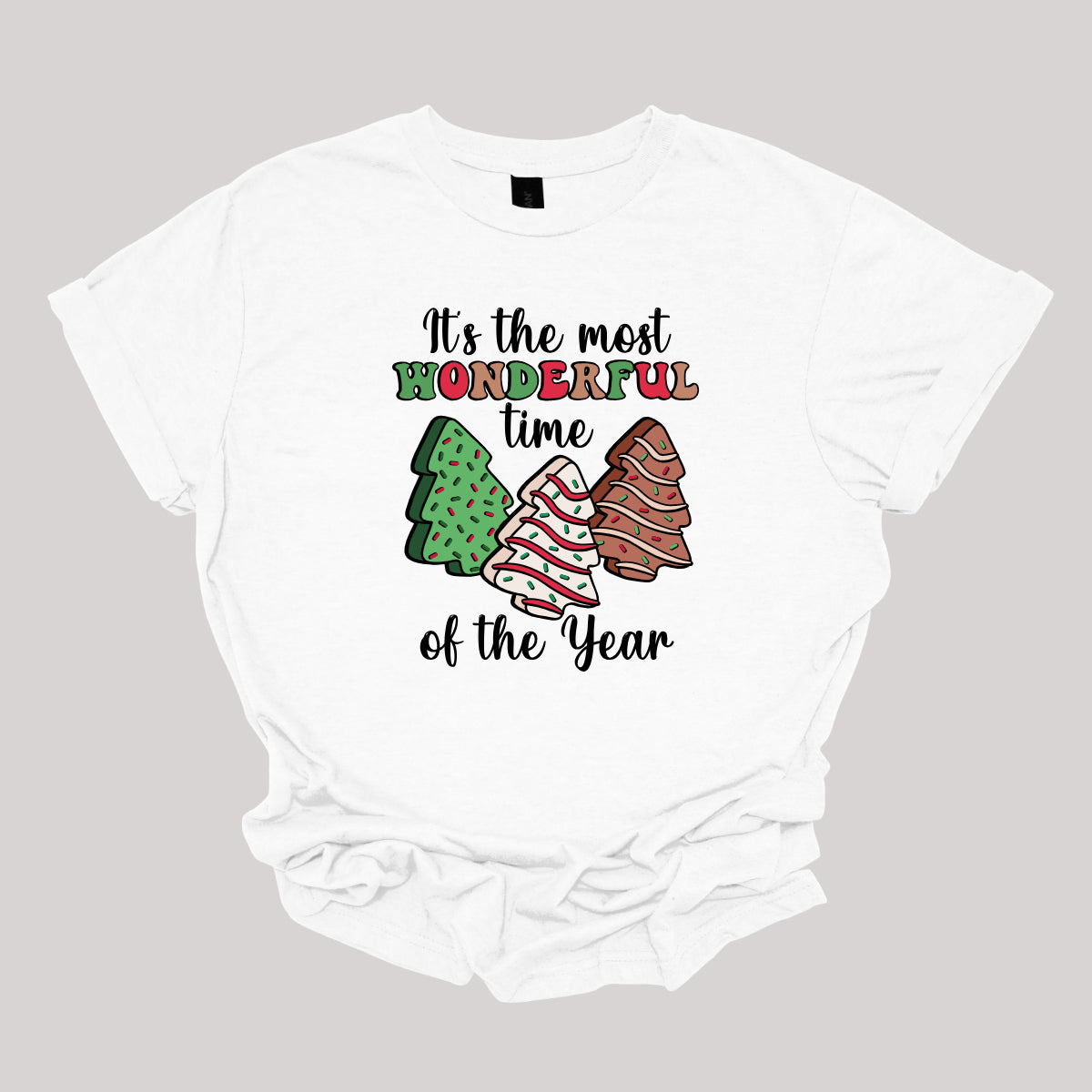 This festive t-shirt features the phrase "It's the most wonderful time of the year" in a stylish black cursive font, creating an elegant backdrop for the holiday message. The word "wonderful" stands out in a playful bubbly font that alternates between vibrant green, cheerful red, and warm brown, adding a whimsical touch. Shop Gorgeousware.com