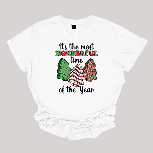 This festive t-shirt features the phrase "It's the most wonderful time of the year" in a stylish black cursive font, creating an elegant backdrop for the holiday message. The word "wonderful" stands out in a playful bubbly font that alternates between vibrant green, cheerful red, and warm brown, adding a whimsical touch. Shop Gorgeousware.com