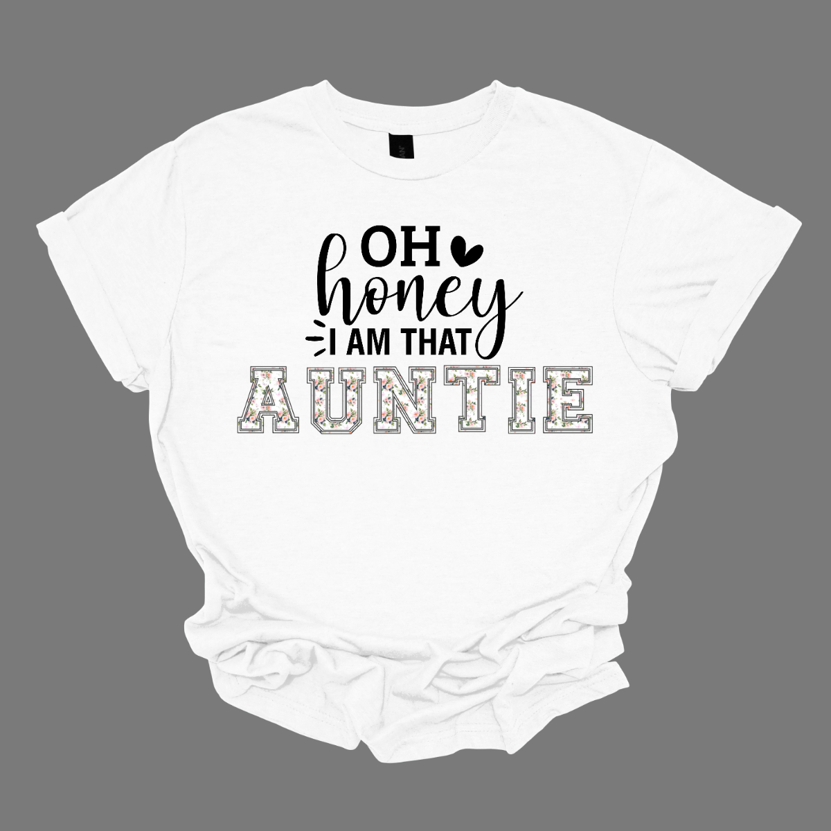 The shirt design features the phrase "Oh Honey, I'm That Auntie" in a playful and eye-catching style. The word "Auntie" is written in bold, bubbly letters filled with intricate floral patterns, giving it a soft and feminine touch. The rest of the phrase uses a mix of fun, whimsical fonts to create a lively and energetic feel. The design is perfect for a stylish and confident auntie who loves to embrace her role with charm and humor. Shop Gorgeouseware.com
