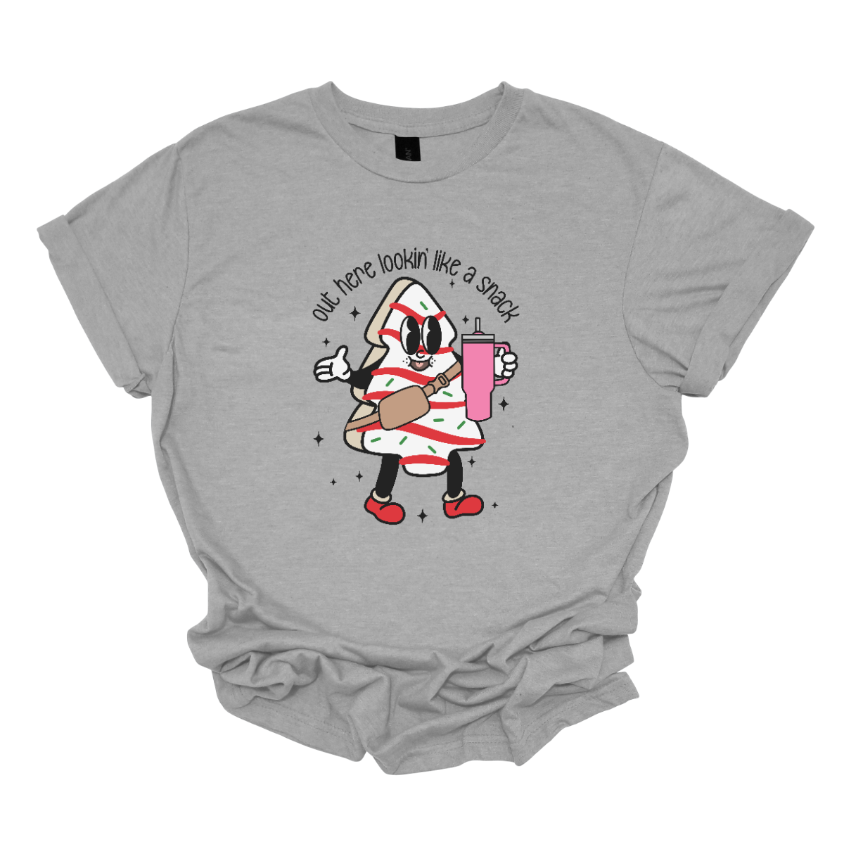 This playful t-shirt features the phrase "Out here lookin' like a snack" in a bold black stick figure font, giving it a fun and casual vibe. Beneath the text, a charming cartoon Christmas tree cake adds a whimsical touch, complete with a cheerful smiling face, a stylish belt bag, and a cup. The surrounding sparkles enhance the festive spirit, making this shirt a delightful choice for spreading holiday cheer with a humorous twist! Shop Gorgeousware.com