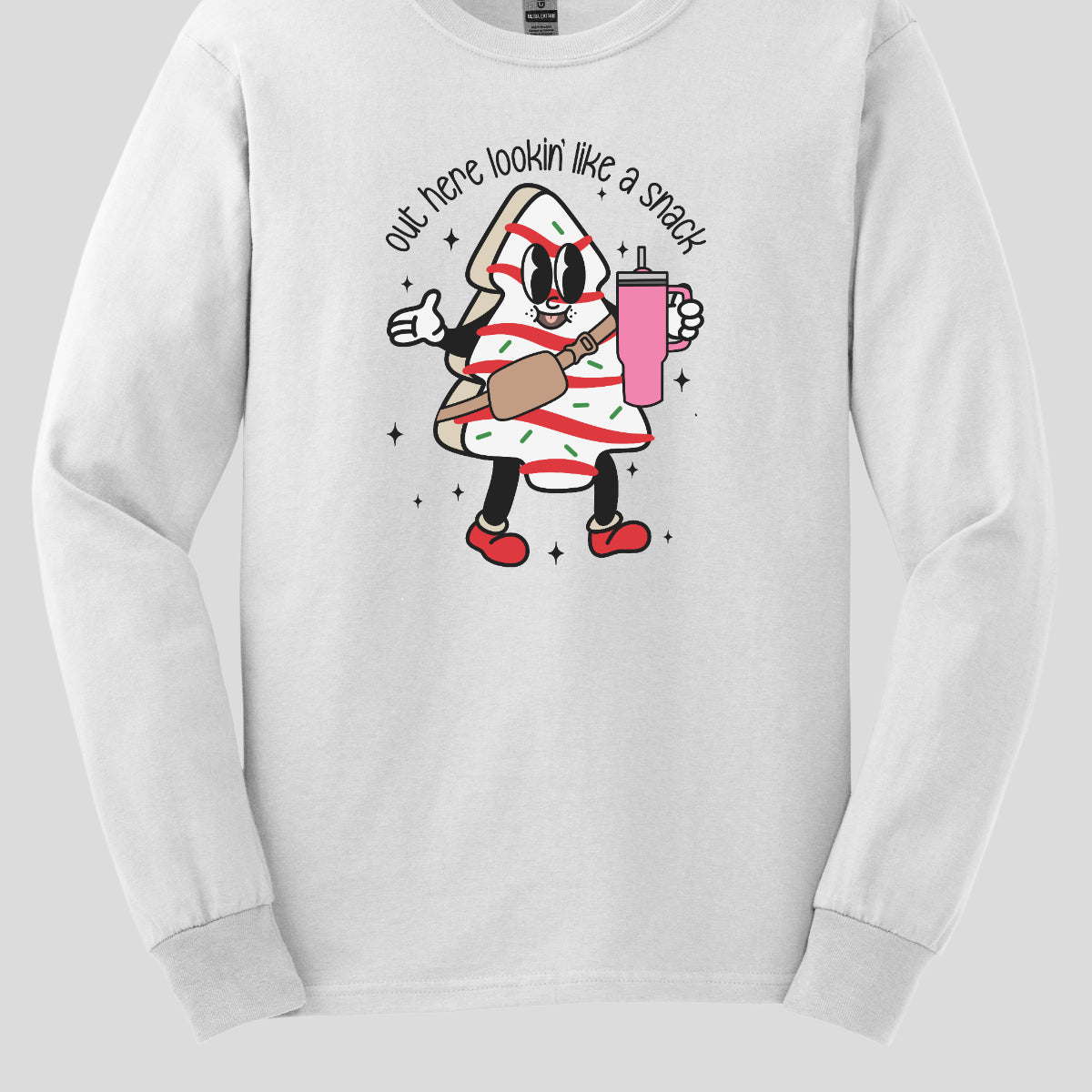 This playful t-shirt features the phrase "Out here lookin' like a snack" in a bold black stick figure font, giving it a fun and casual vibe. Beneath the text, a charming cartoon Christmas tree cake adds a whimsical touch, complete with a cheerful smiling face, a stylish belt bag, and a cup. The surrounding sparkles enhance the festive spirit, making this shirt a delightful choice for spreading holiday cheer with a humorous twist! Shop Gorgeousware.com