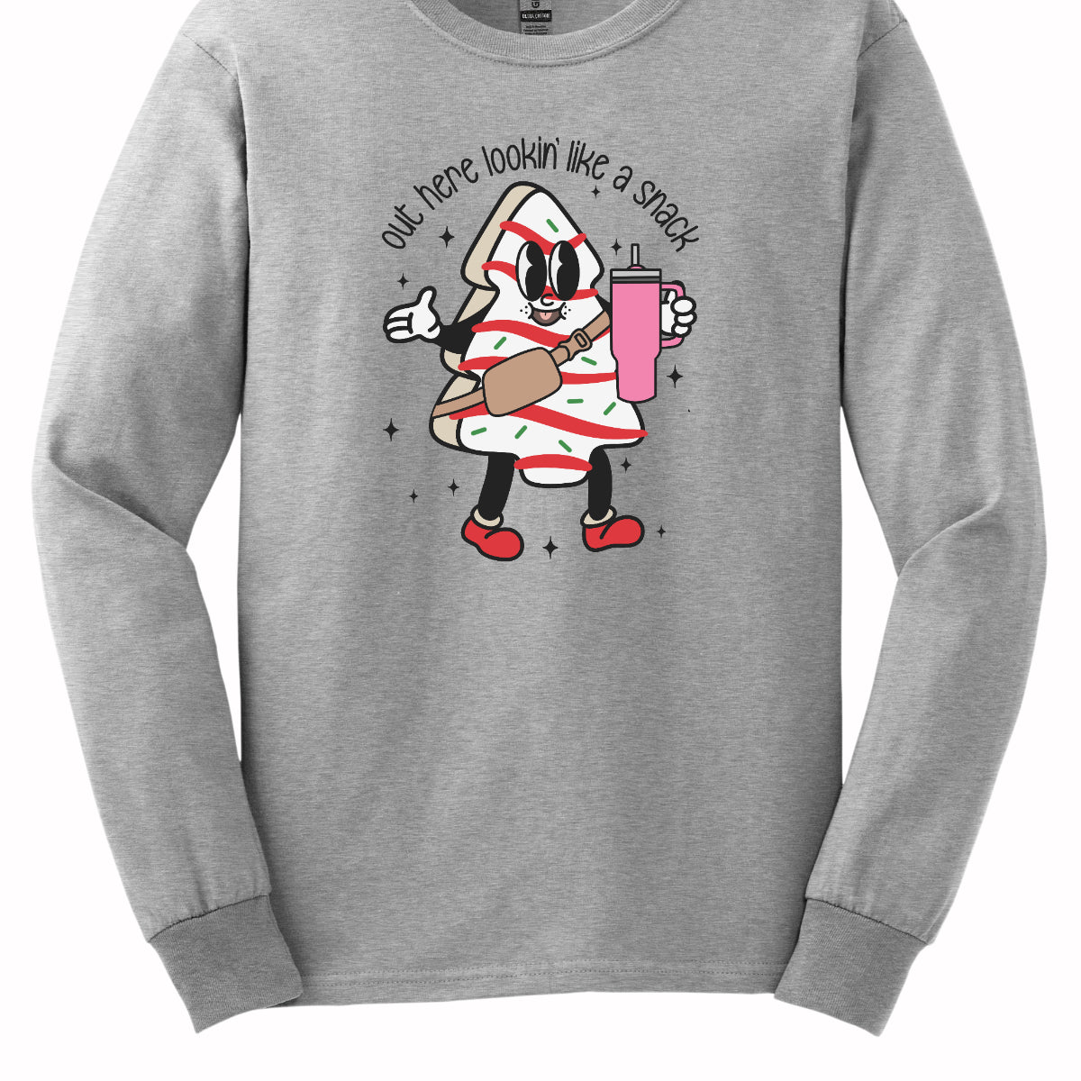 This playful t-shirt features the phrase "Out here lookin' like a snack" in a bold black stick figure font, giving it a fun and casual vibe. Beneath the text, a charming cartoon Christmas tree cake adds a whimsical touch, complete with a cheerful smiling face, a stylish belt bag, and a cup. The surrounding sparkles enhance the festive spirit, making this shirt a delightful choice for spreading holiday cheer with a humorous twist! Shop Gorgeousware.com