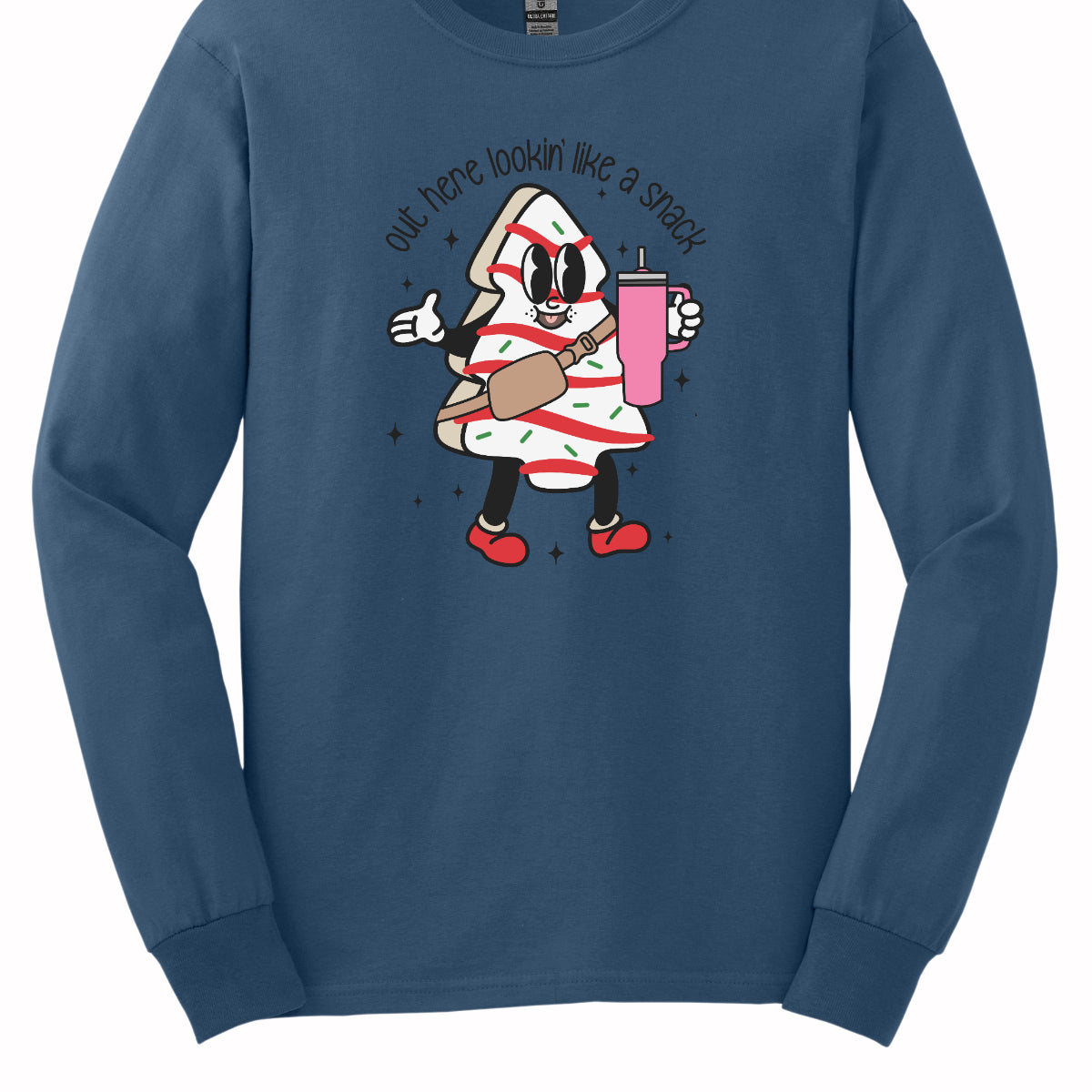 This playful t-shirt features the phrase "Out here lookin' like a snack" in a bold black stick figure font, giving it a fun and casual vibe. Beneath the text, a charming cartoon Christmas tree cake adds a whimsical touch, complete with a cheerful smiling face, a stylish belt bag, and a cup. The surrounding sparkles enhance the festive spirit, making this shirt a delightful choice for spreading holiday cheer with a humorous twist! Shop Gorgeousware.com