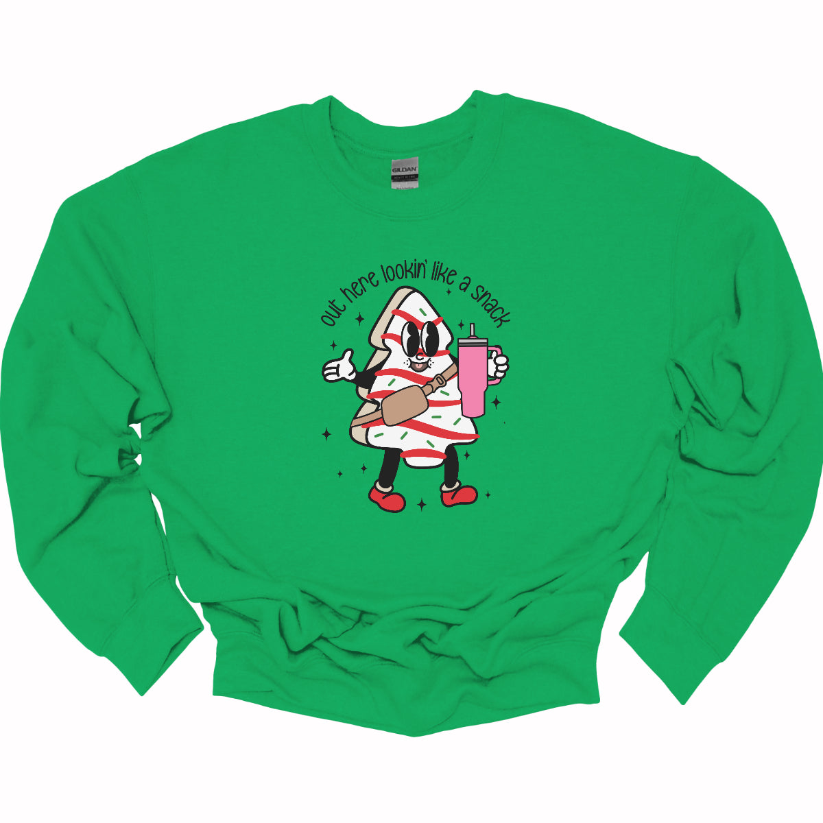 This playful t-shirt features the phrase "Out here lookin' like a snack" in a bold black stick figure font, giving it a fun and casual vibe. Beneath the text, a charming cartoon Christmas tree cake adds a whimsical touch, complete with a cheerful smiling face, a stylish belt bag, and a cup. The surrounding sparkles enhance the festive spirit, making this shirt a delightful choice for spreading holiday cheer with a humorous twist! Shop Gorgeousware.com