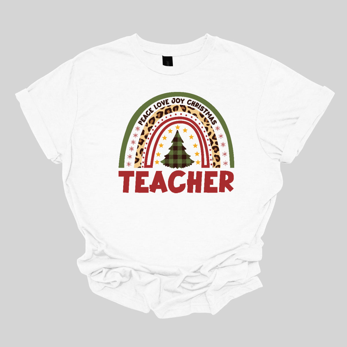 The t-shirt design features a vibrant, patterned rainbow that arcs gracefully across the fabric. Each color of the rainbow is adorned with playful patterns, such as polka dots, snowflakes, and cheetah print, adding a whimsical touch. At the center of the rainbow stands a beautifully illustrated Christmas tree. Shop at orgeousware.com