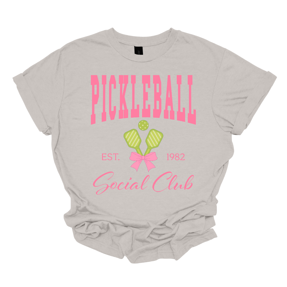 The shirt design features the phrase "Pickleball Social Club" in bold, hot pink font, giving it a fun and vibrant look. Below, "Est. 1982" is displayed in a stylish, slightly smaller font, adding a touch of vintage charm.
Two pickleball paddles are crossed in the center, creating a dynamic focal point, with a pickleball placed between them to emphasize the sport. A pink bow is tied around the intersection of the paddles, adding a playful and fashionable touch. Shop Gorgeousware.com