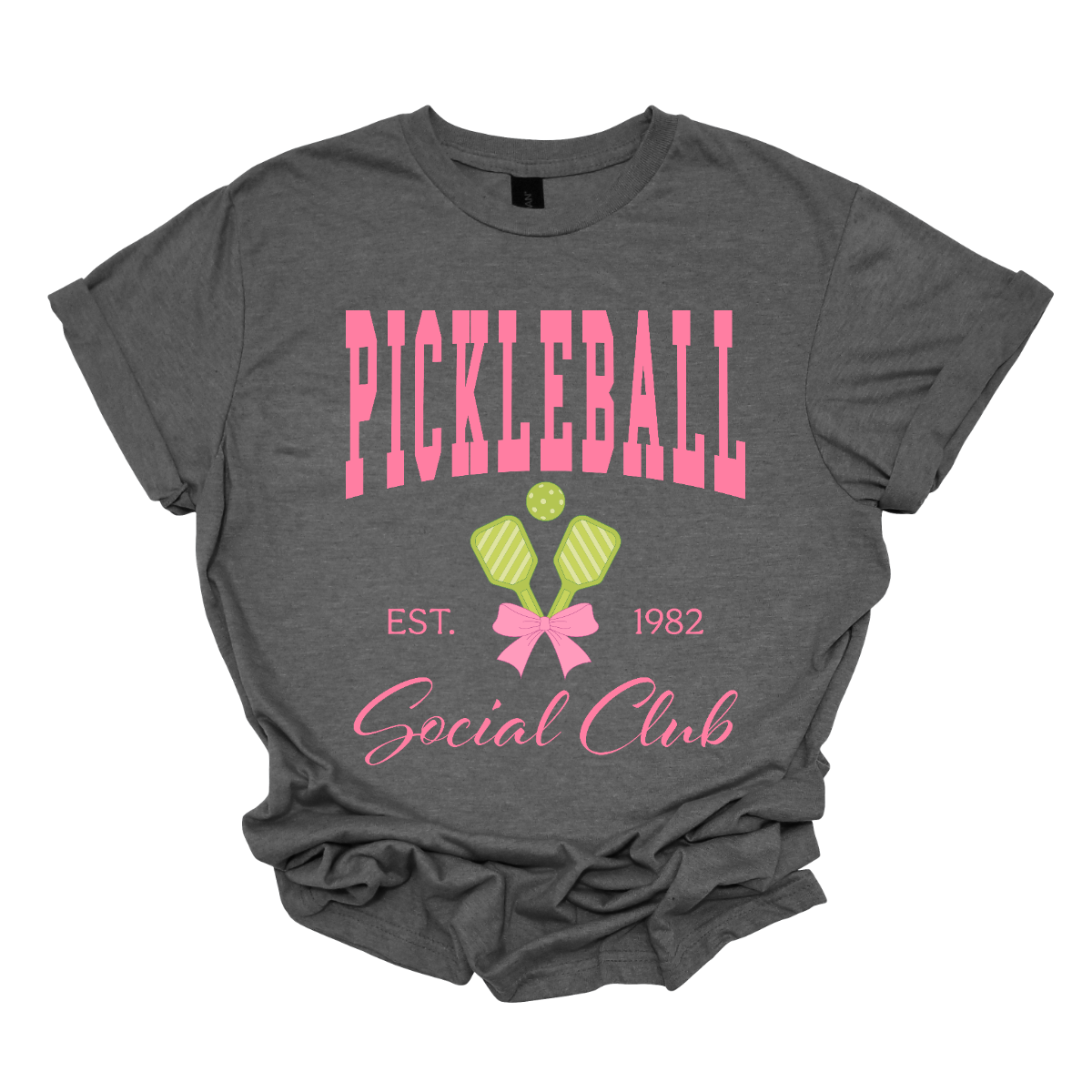 The shirt design features the phrase "Pickleball Social Club" in bold, hot pink font, giving it a fun and vibrant look. Below, "Est. 1982" is displayed in a stylish, slightly smaller font, adding a touch of vintage charm.
Two pickleball paddles are crossed in the center, creating a dynamic focal point, with a pickleball placed between them to emphasize the sport. A pink bow is tied around the intersection of the paddles, adding a playful and fashionable touch. Shop Gorgeousware.com