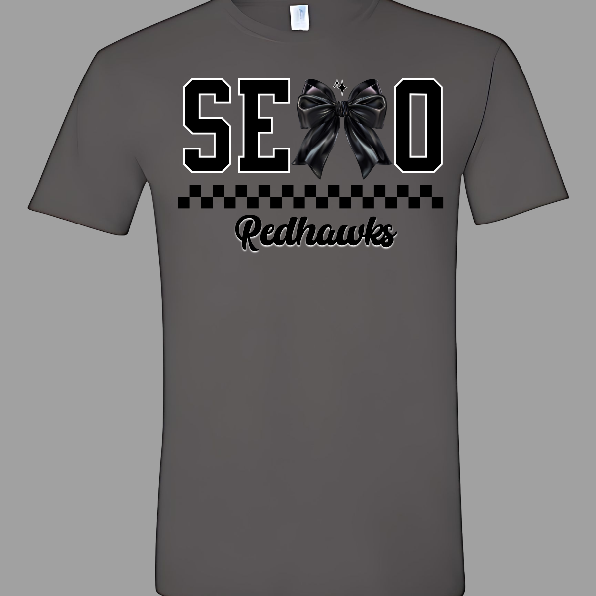 Show off your SEMO pride in style with this trendy short sleeve t-shirt! Featuring the bold letters "SEMO," where the "M" is cleverly replaced by a stylish black croquette bow, this shirt adds a unique twist to your wardrobe. Underneath, a playful checkerboard stripe adds a fun touch, while "Redhawks" is elegantly written in a cute cursive font, bringing a touch of flair. Shop at Gorgeousware.com