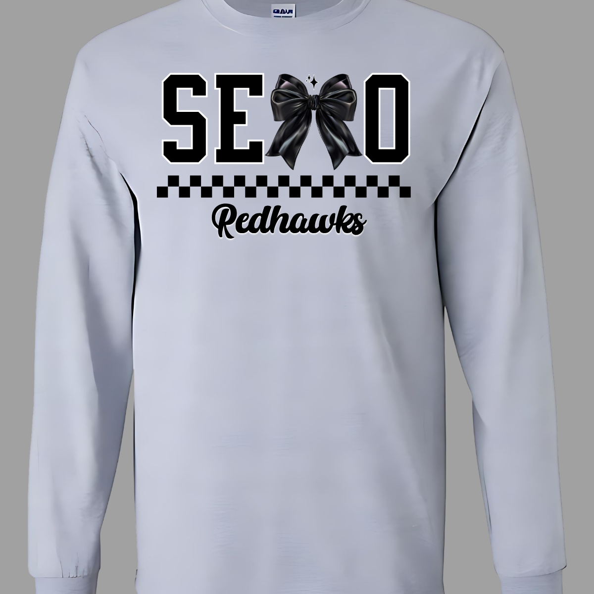 Show off your SEMO pride in style with this trendy short sleeve t-shirt! Featuring the bold letters "SEMO," where the "M" is cleverly replaced by a stylish black croquette bow, this shirt adds a unique twist to your wardrobe. Underneath, a playful checkerboard stripe adds a fun touch, while "Redhawks" is elegantly written in a cute cursive font, bringing a touch of flair. Shop at Gorgeousware.com