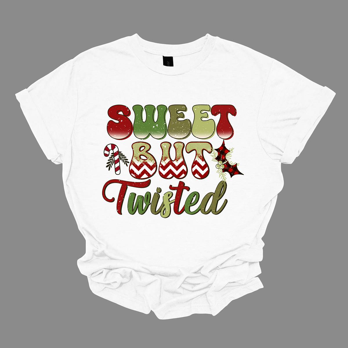 The apparel features a playful and bold design with the phrase "Sweet but Twisted" prominently displayed in large bubble letters. The letters are vibrant, with shades of green and red, creating a fun, festive contrast. The word "but" stands out, with its bottom edges filled with a red and white chevron pattern, adding a striking visual detail. Shop at Gorgeousware.com