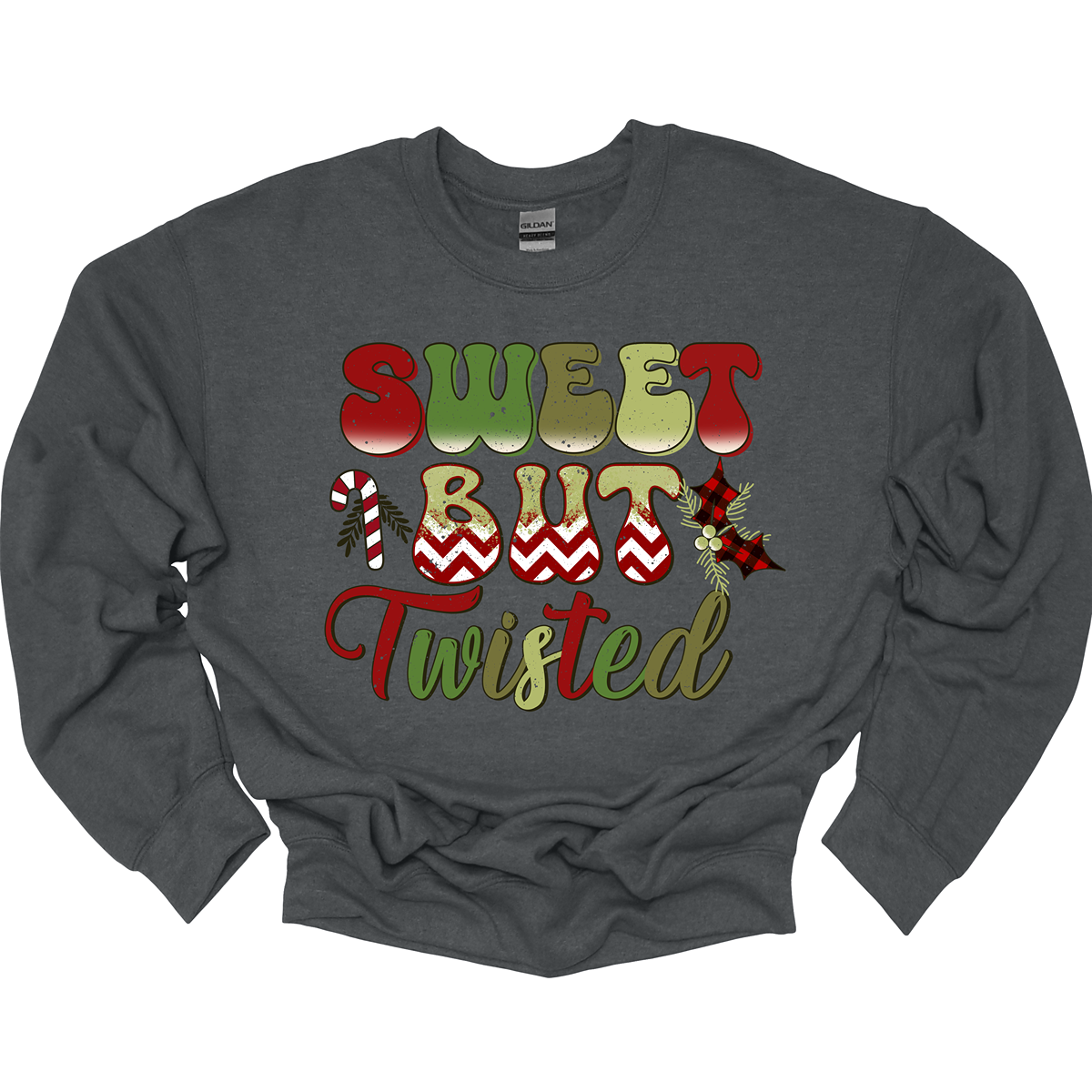The apparel features a playful and bold design with the phrase "Sweet but Twisted" prominently displayed in large bubble letters. The letters are vibrant, with shades of green and red, creating a fun, festive contrast. The word "but" stands out, with its bottom edges filled with a red and white chevron pattern, adding a striking visual detail. Shop at Gorgeousware.com