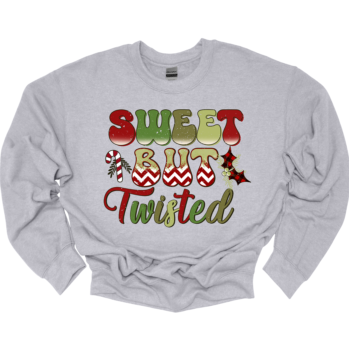 The apparel features a playful and bold design with the phrase "Sweet but Twisted" prominently displayed in large bubble letters. The letters are vibrant, with shades of green and red, creating a fun, festive contrast. The word "but" stands out, with its bottom edges filled with a red and white chevron pattern, adding a striking visual detail. Shop at Gorgeousware.com