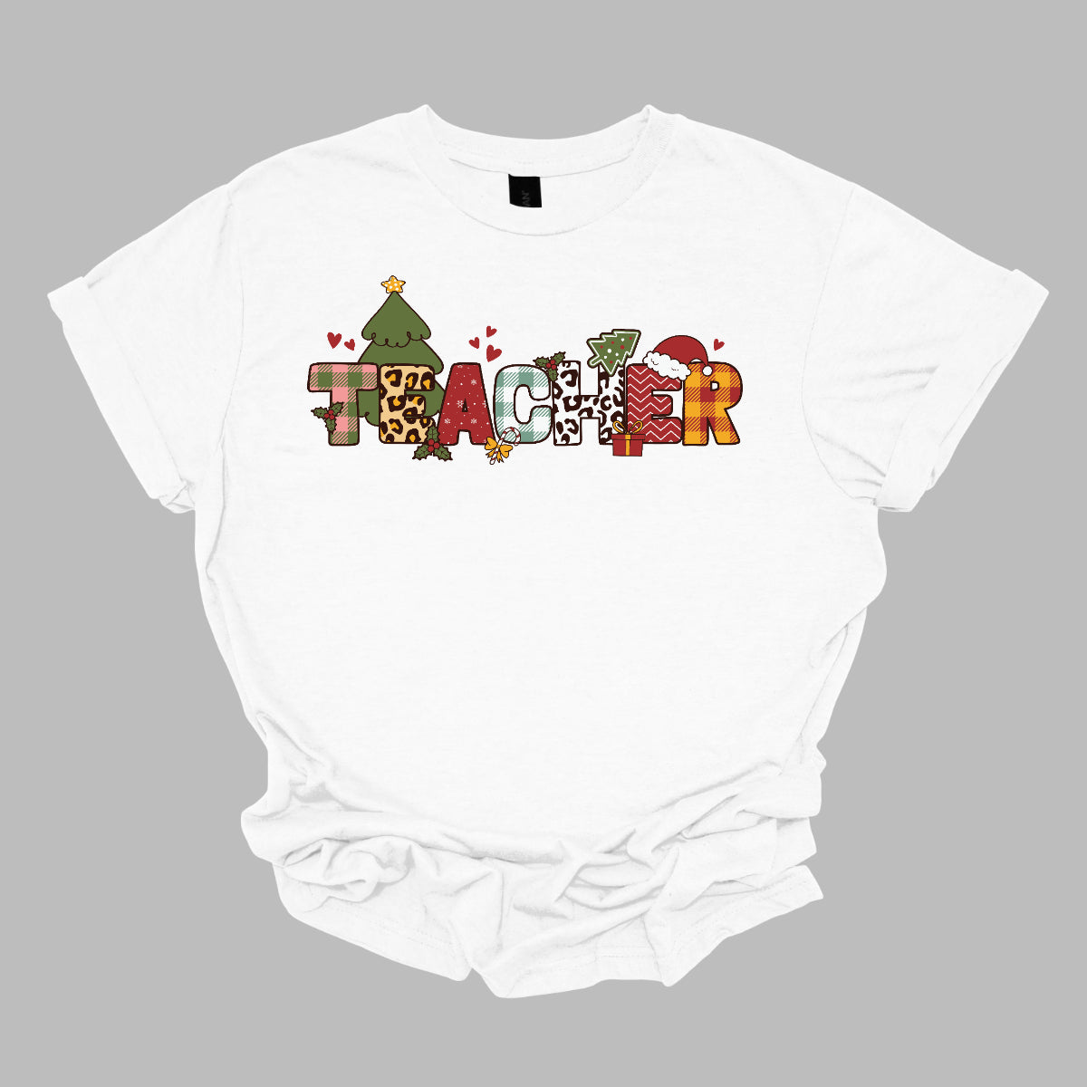 This eye-catching t-shirt boldly displays the word "TEACHER" in large block letters, each letter showcasing a unique style of print that adds a fun and creative flair. Behind the first "E," a cheerful Christmas tree adds a festive touch, while the second "E" is adorned with a cute Santa hat, making it even more playful. Shop Gorgeouswre.com