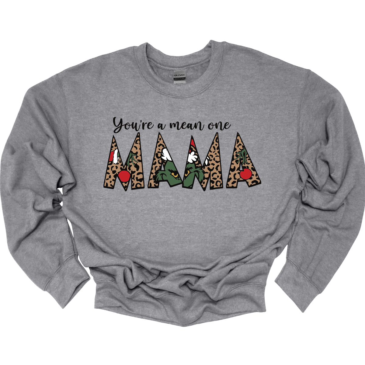 The phrase "You're a Mean One Mama" takes center stage, with "You're a Mean One" written in elegant black cursive font that flows beautifully across the fabric. The standout element is the word "Mama," which is rendered in bold, eye-catching letters. Each letter of "Mama" is filled with a quirky depiction of the Grinch, set against a vibrant cheetah print background. Shop Gorgeousware.com