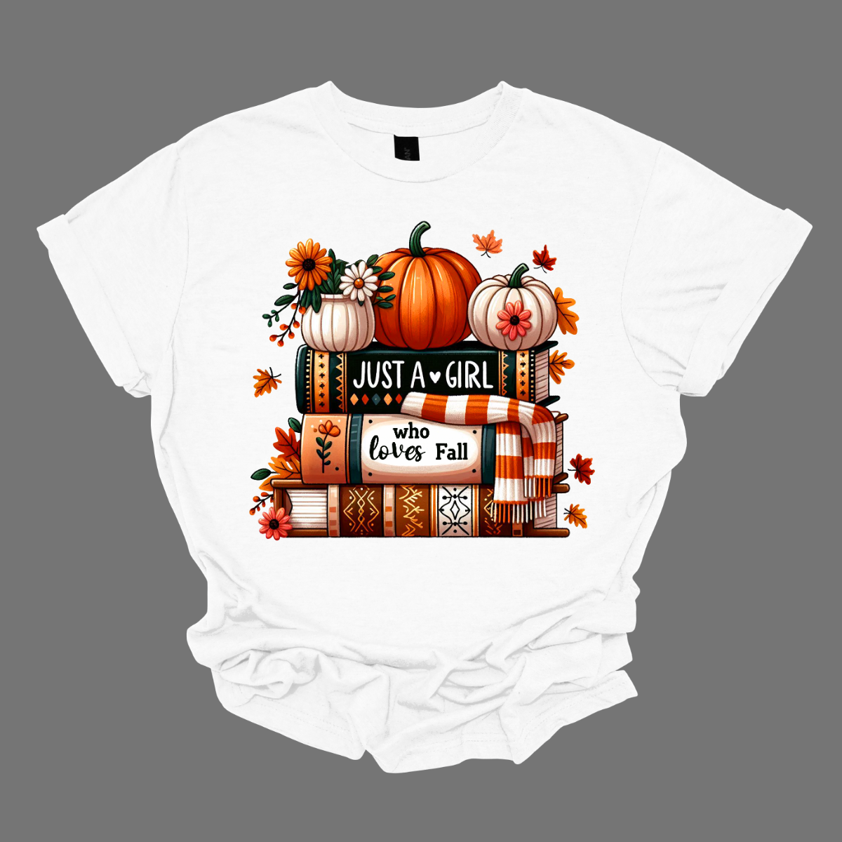 Bring cozy fall vibes to your wardrobe with this autumn-inspired graphic tee! The design features two pumpkins and a small pot of flowers perched on a stack of books with the spines reading “Just a Girl” and “Who Loves Fall.” An orange-and-white scarf wraps around the books while leaves gently fall, creating the perfect scene for autumn lovers. Shop at Gorgeousware.com