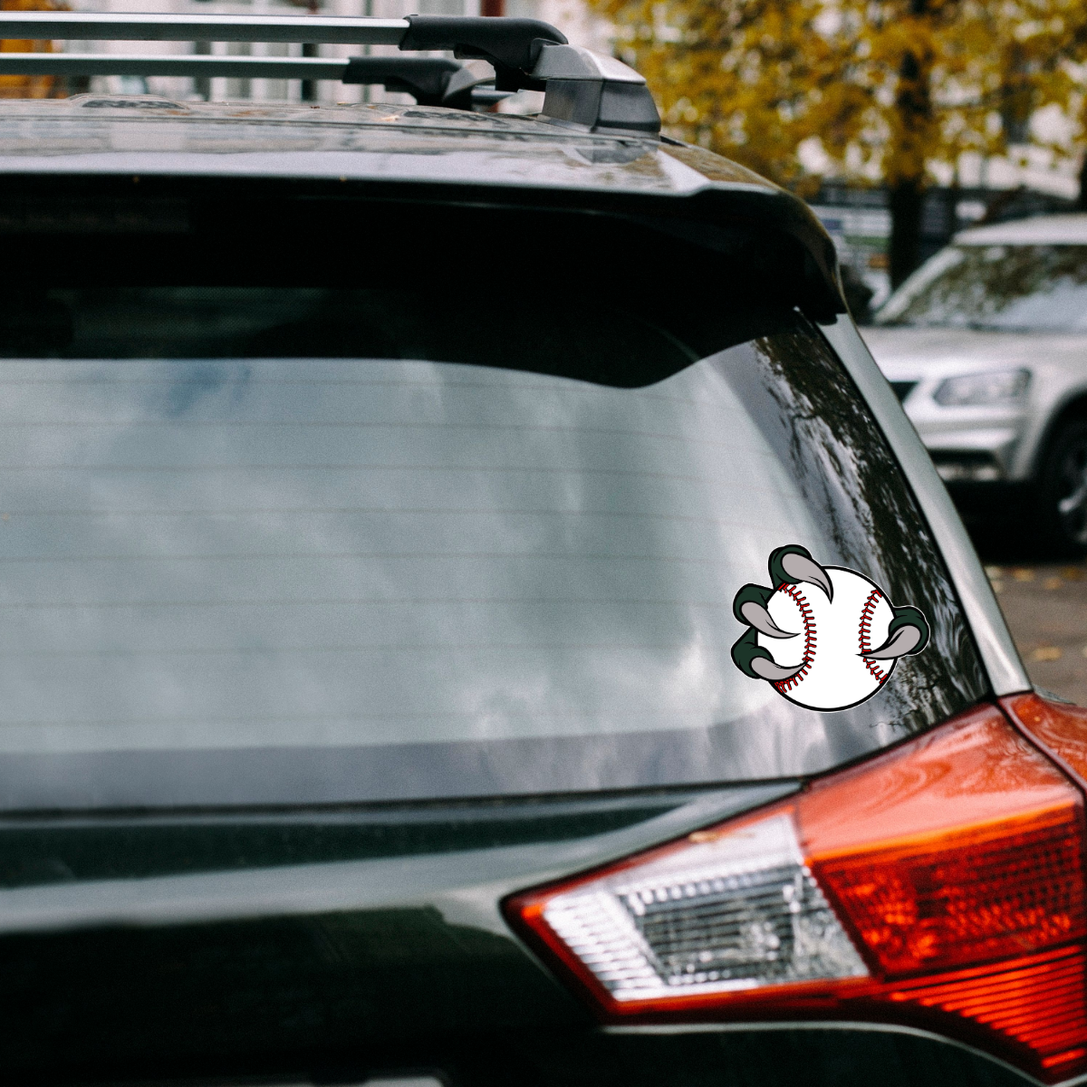 Car with a baseball-themed decal on the rear window, parked outdoors.